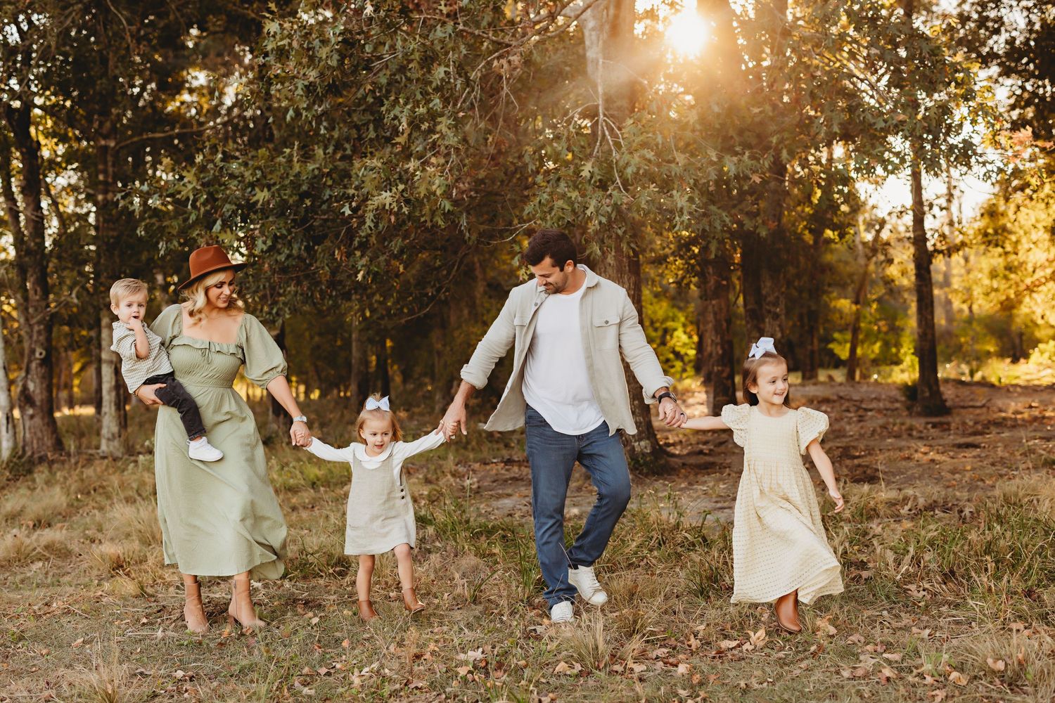 Sunset family portrait in wooded setting with natural golden light filtering through trees.