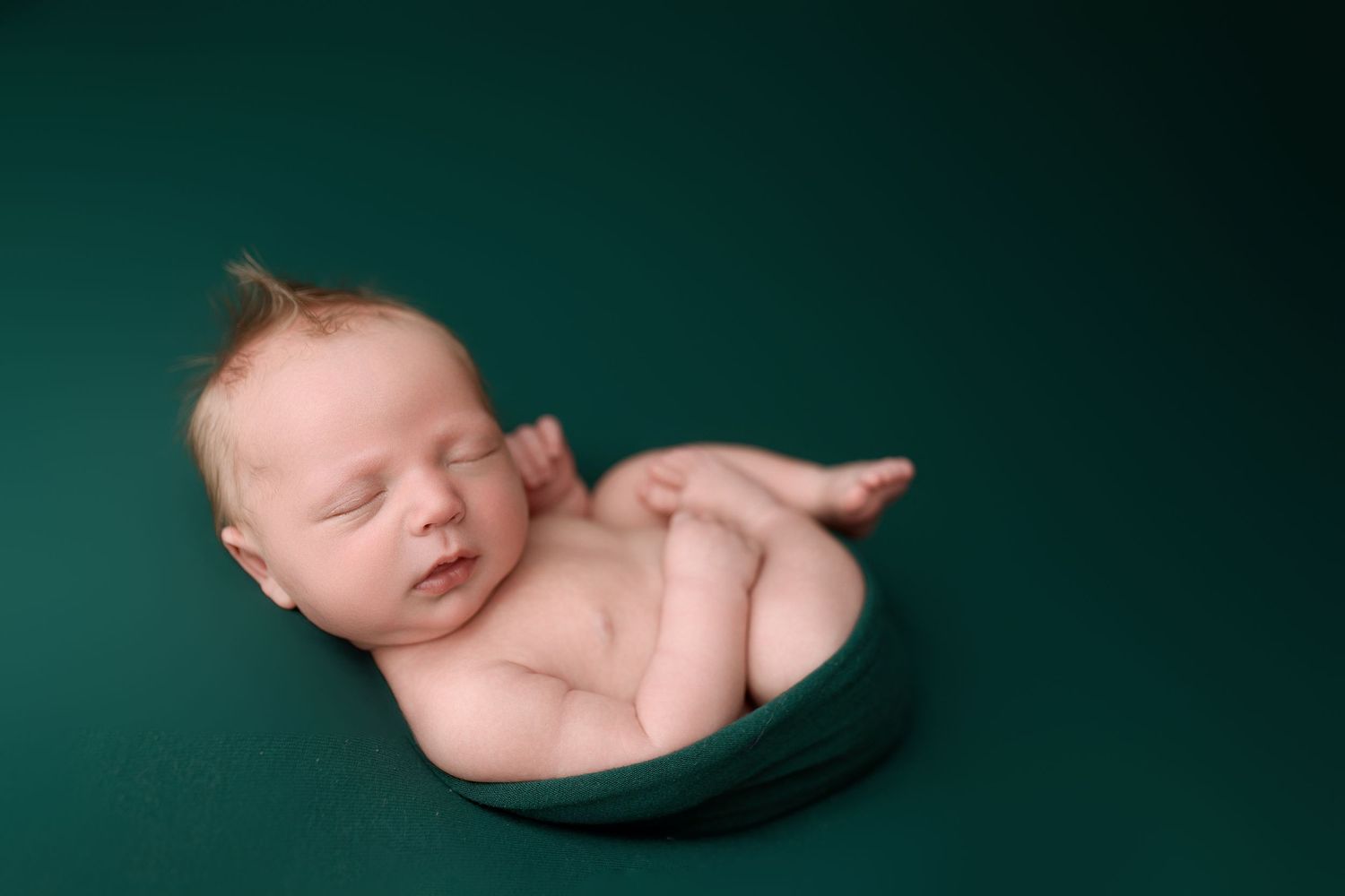 A series of artistic newborn photography poses against a dark green background showing curled up sleeping positions.