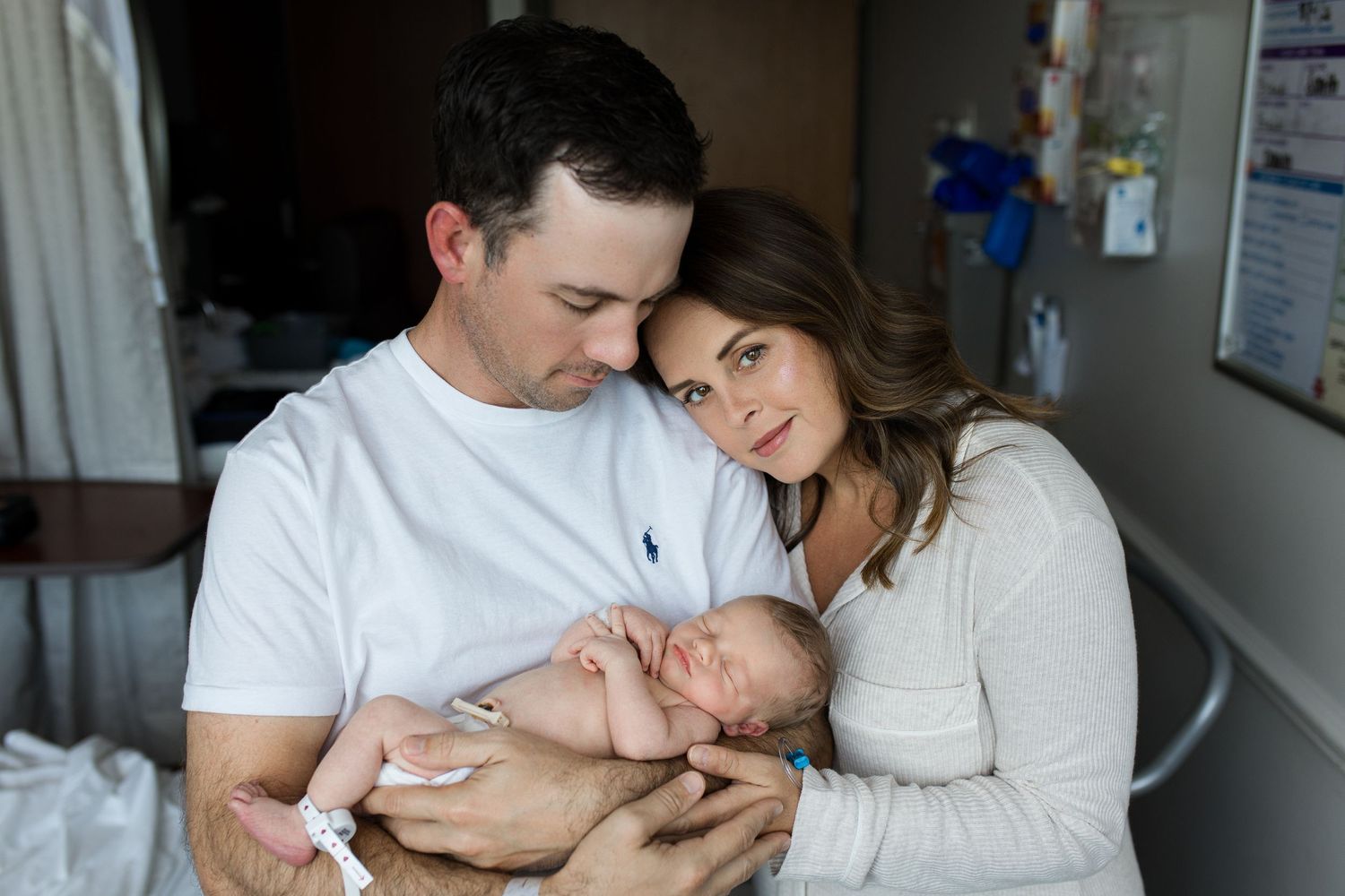 New parents holding their sleeping newborn baby in a hospital room shortly after birth during Fresh 48 session with Bree Elle Photography.