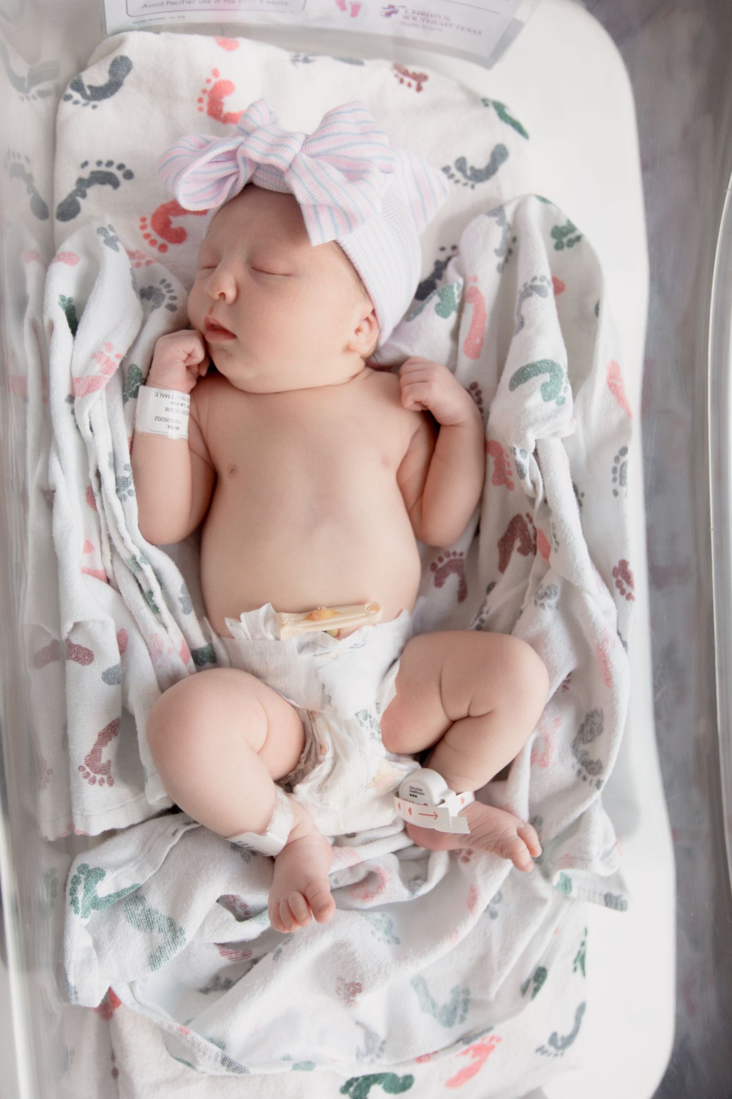 Overhead view of sleeping infant wrapped in delicate white blanket with animal prints.
