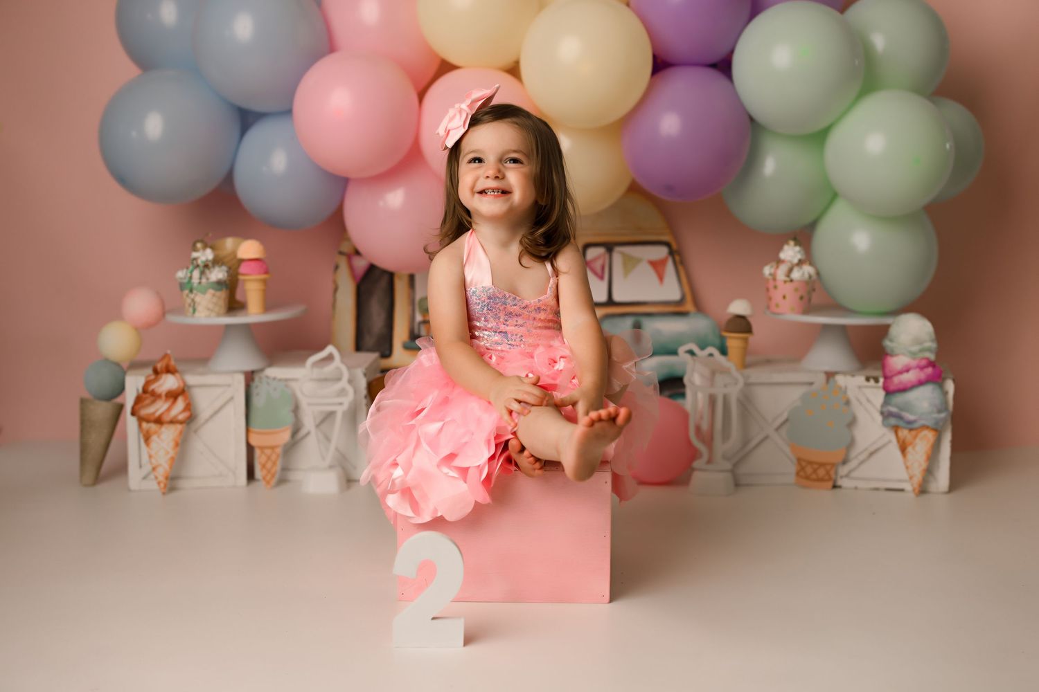 A festive birthday setup with pastel balloons, pink decor, and a number 2 prop for a toddler celebration.
