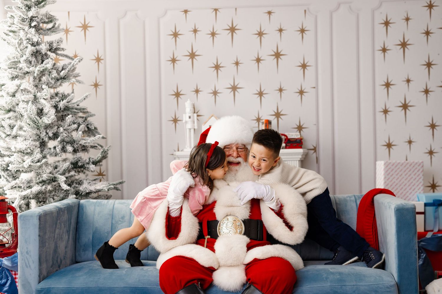 A festive Christmas photoshoot setup with a white backdrop, twinkling star lights, and red and white holiday decor.