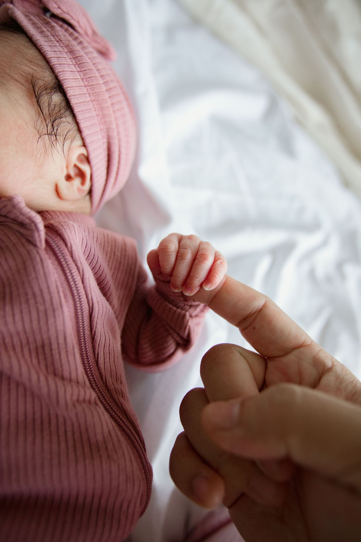Close-up of a baby's small hand reaching for an adult finger.