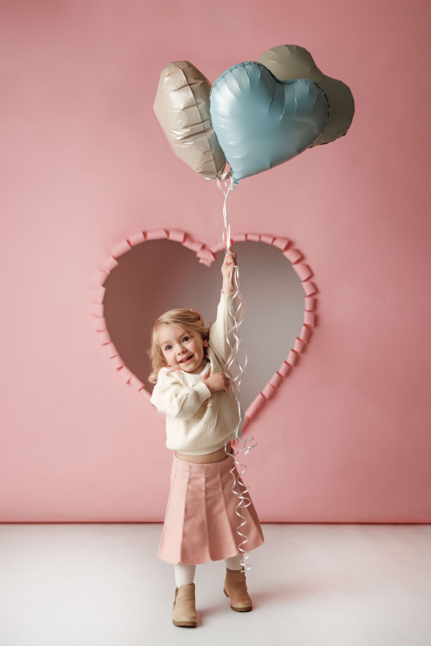 Valentine's themed photo setup with heart backdrop and pastel blue balloons.
