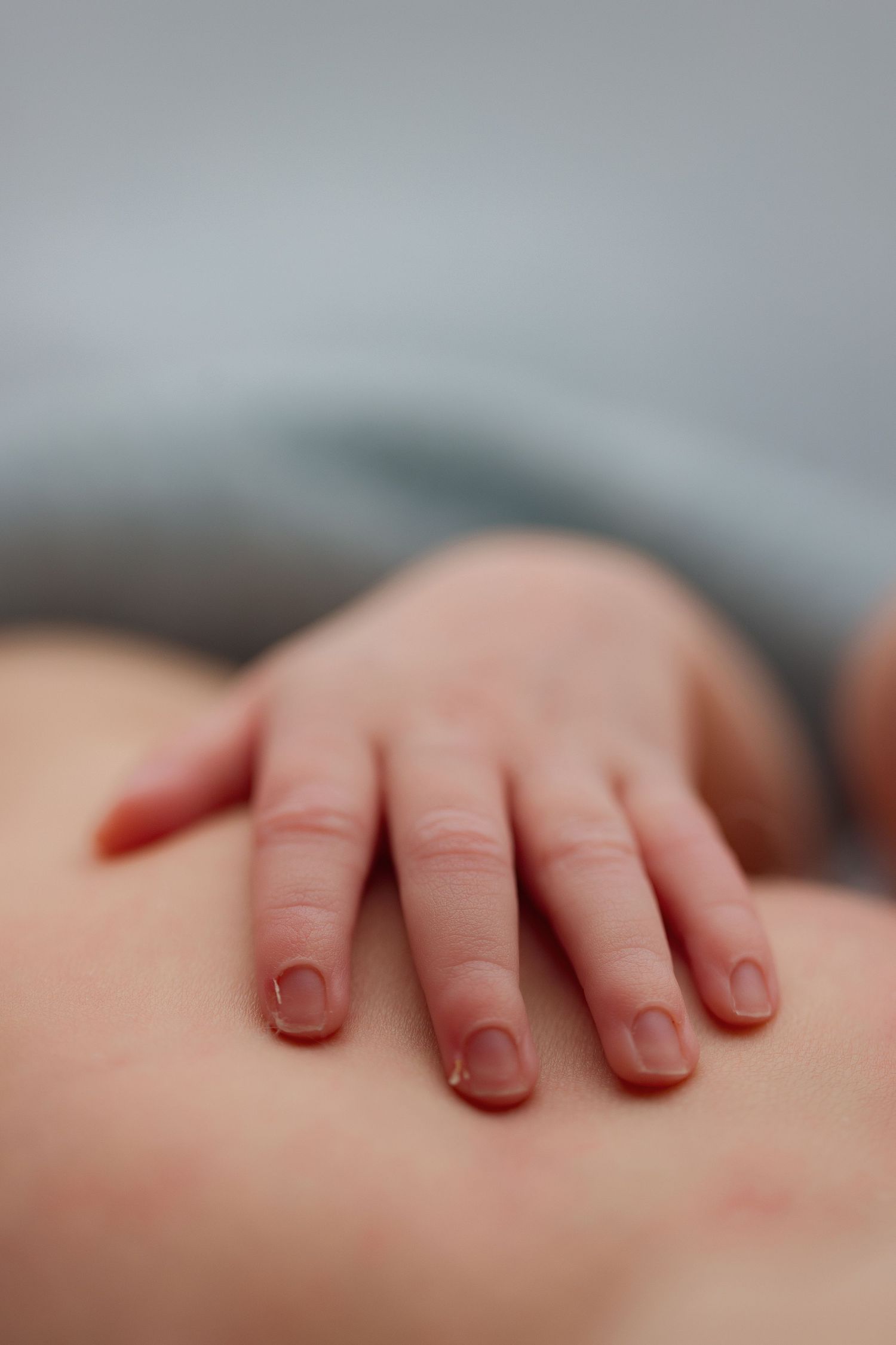 Close-up detail shot of tiny newborn fingers against soft background.