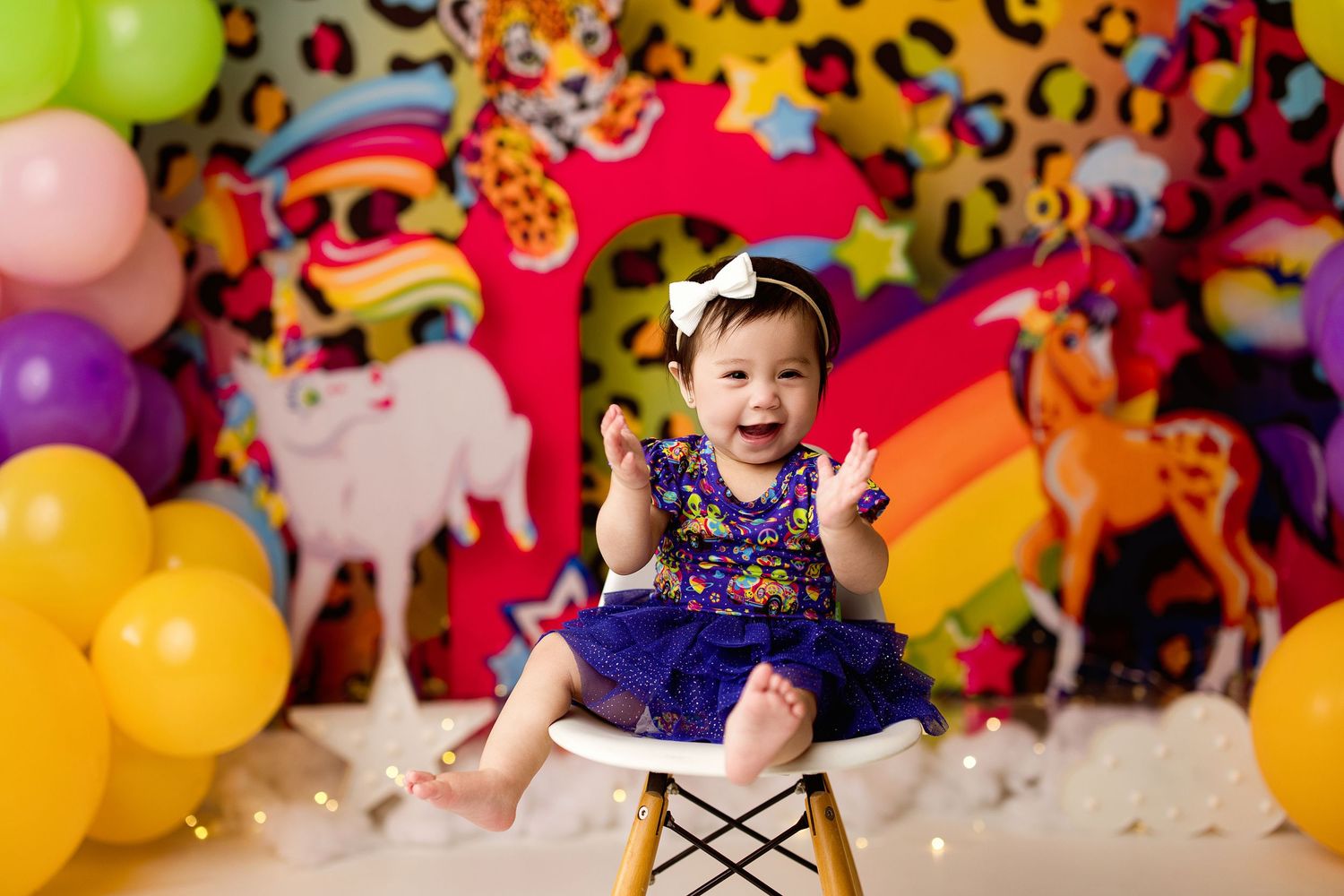 Colorful birthday party setup with rainbow balloons, leopard print backdrop, and sparkly decorations for a festive celebration.