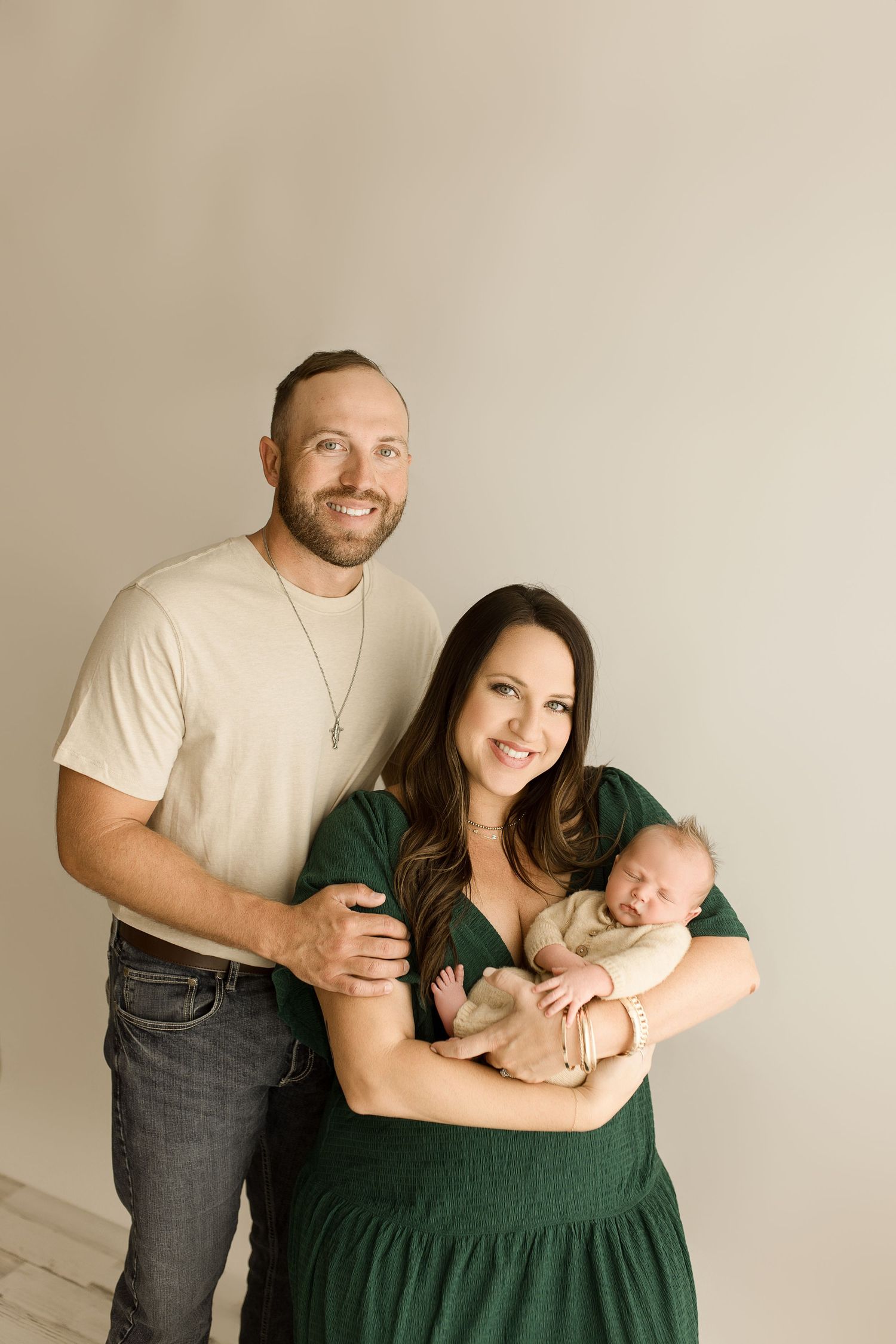 Family portrait session showing tender moments between parents and infant in neutral tones.
