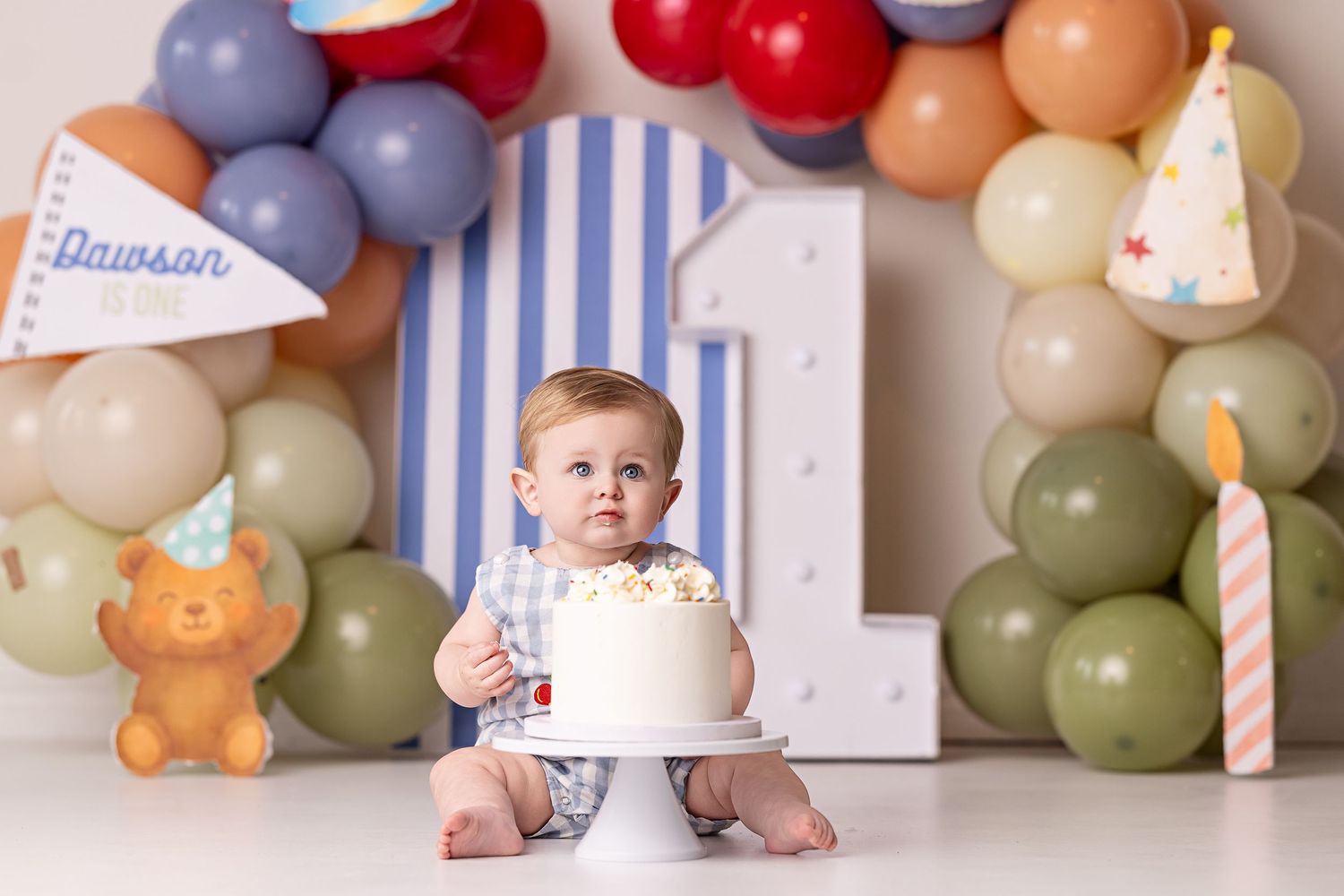 A birthday party setup with pastel balloon garlands, striped banners, and soft decorative elements in blue and white tones.