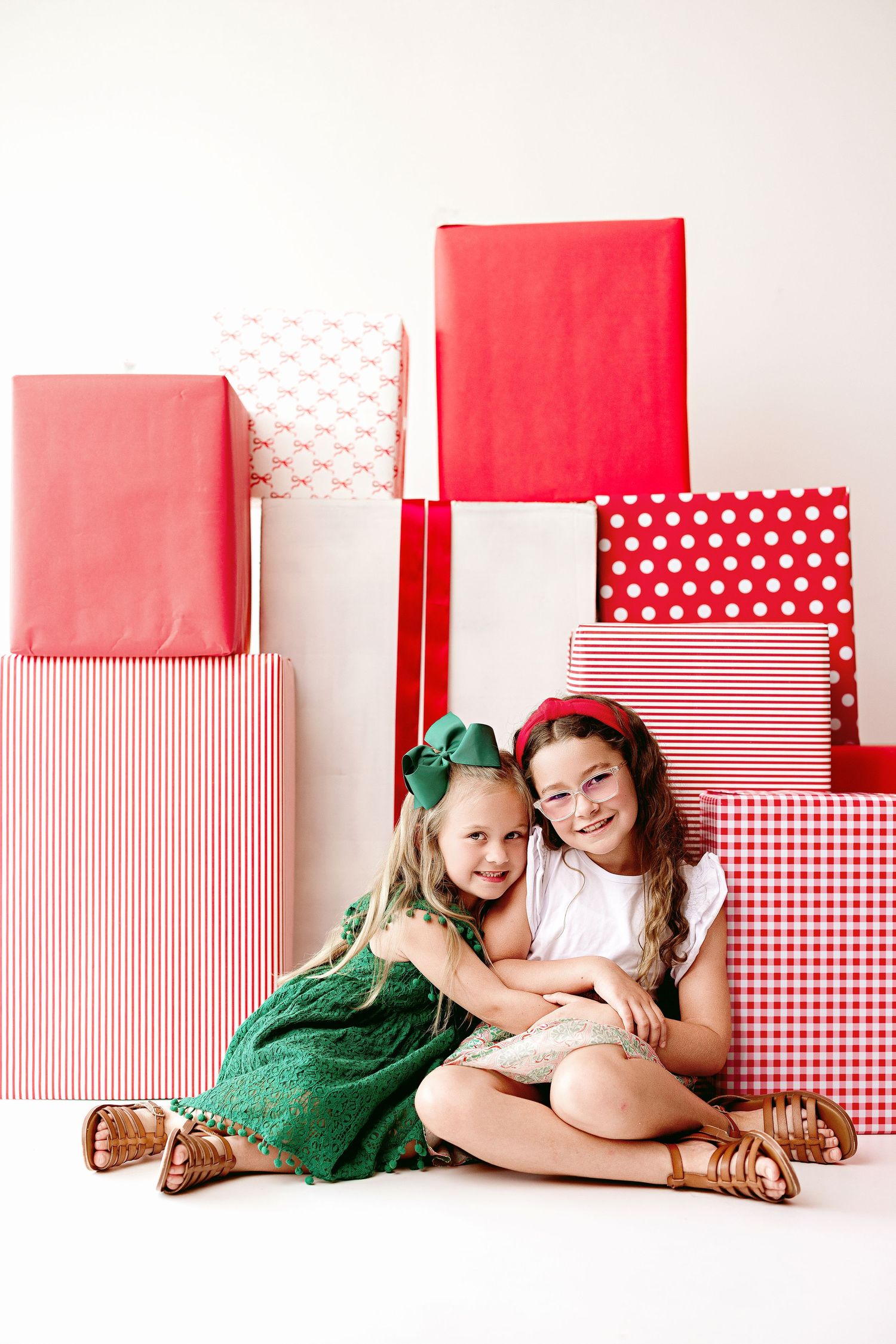 Holiday photo setup with red and white wrapped presents and decorative boxes arranged against a plain white background.