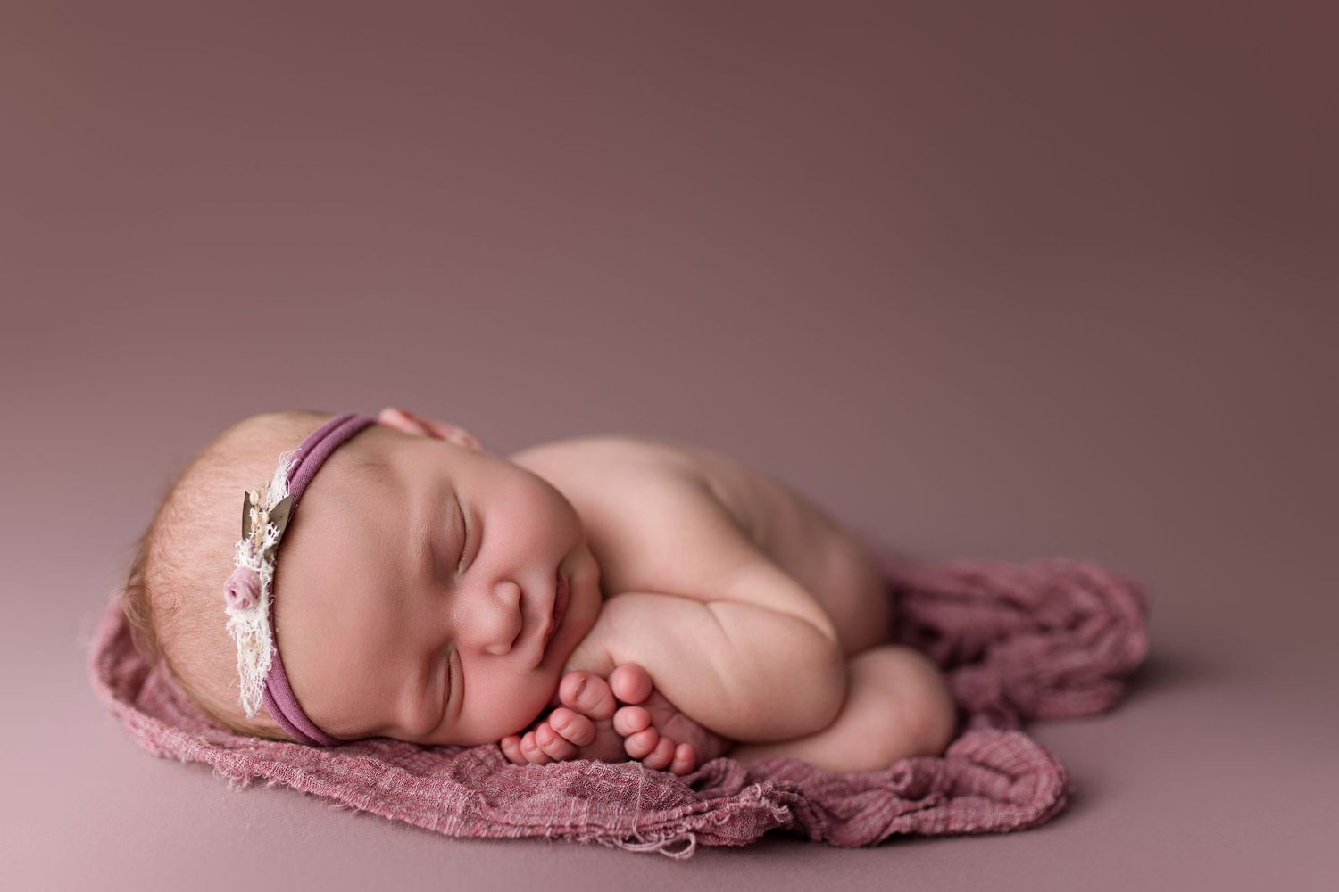 A series of images showing a sleeping newborn baby on a pink blanket in different poses.