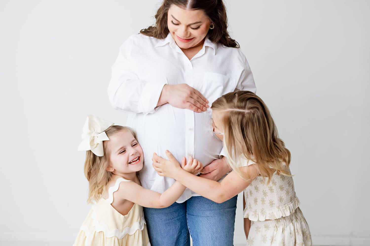 Candid family moment with young children touching mother's pregnant belly with Bree Elle Photography in Silsbee, TX.