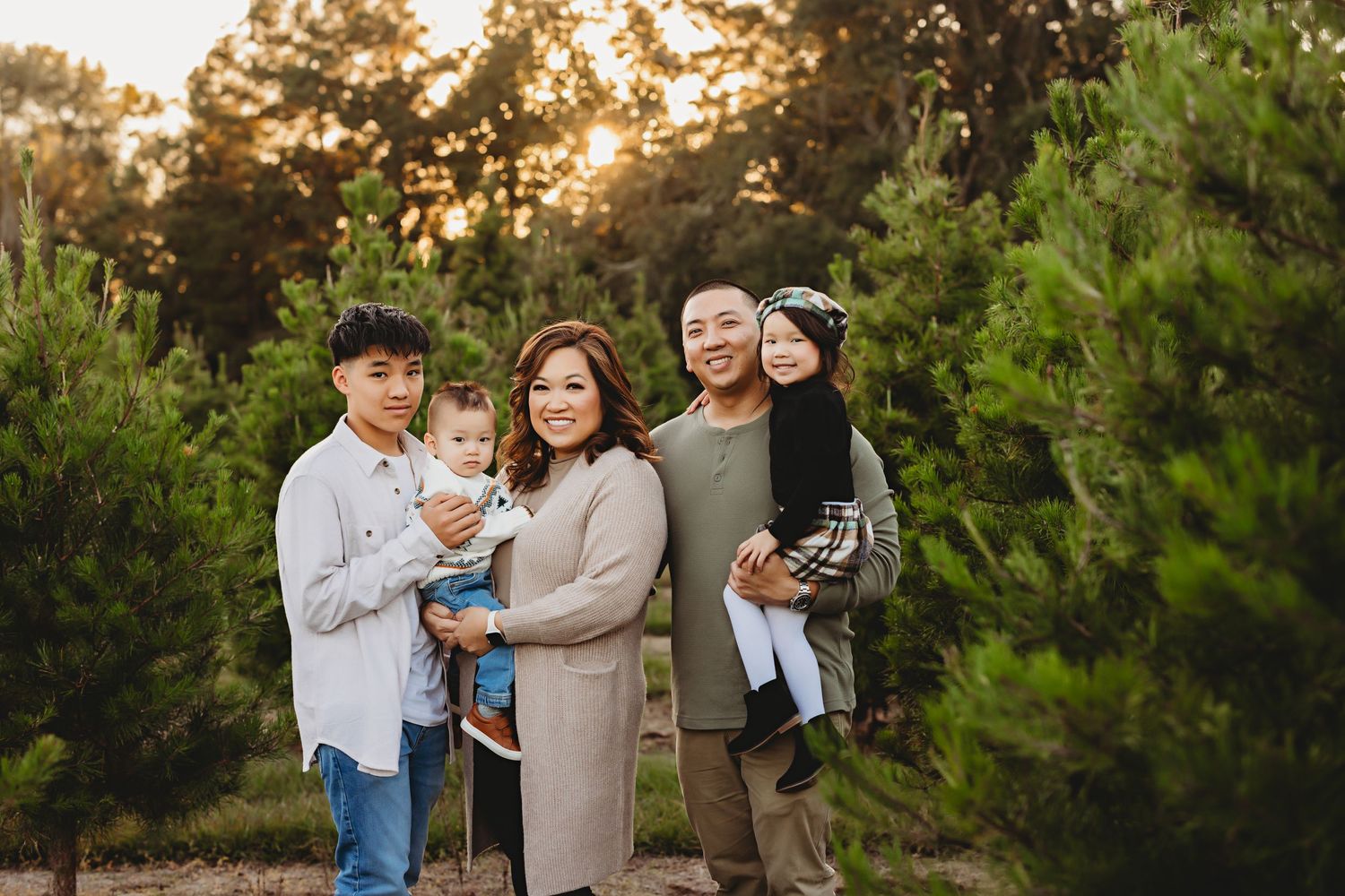 Outdoor family photoshoot in pine forest during golden hour sunset.