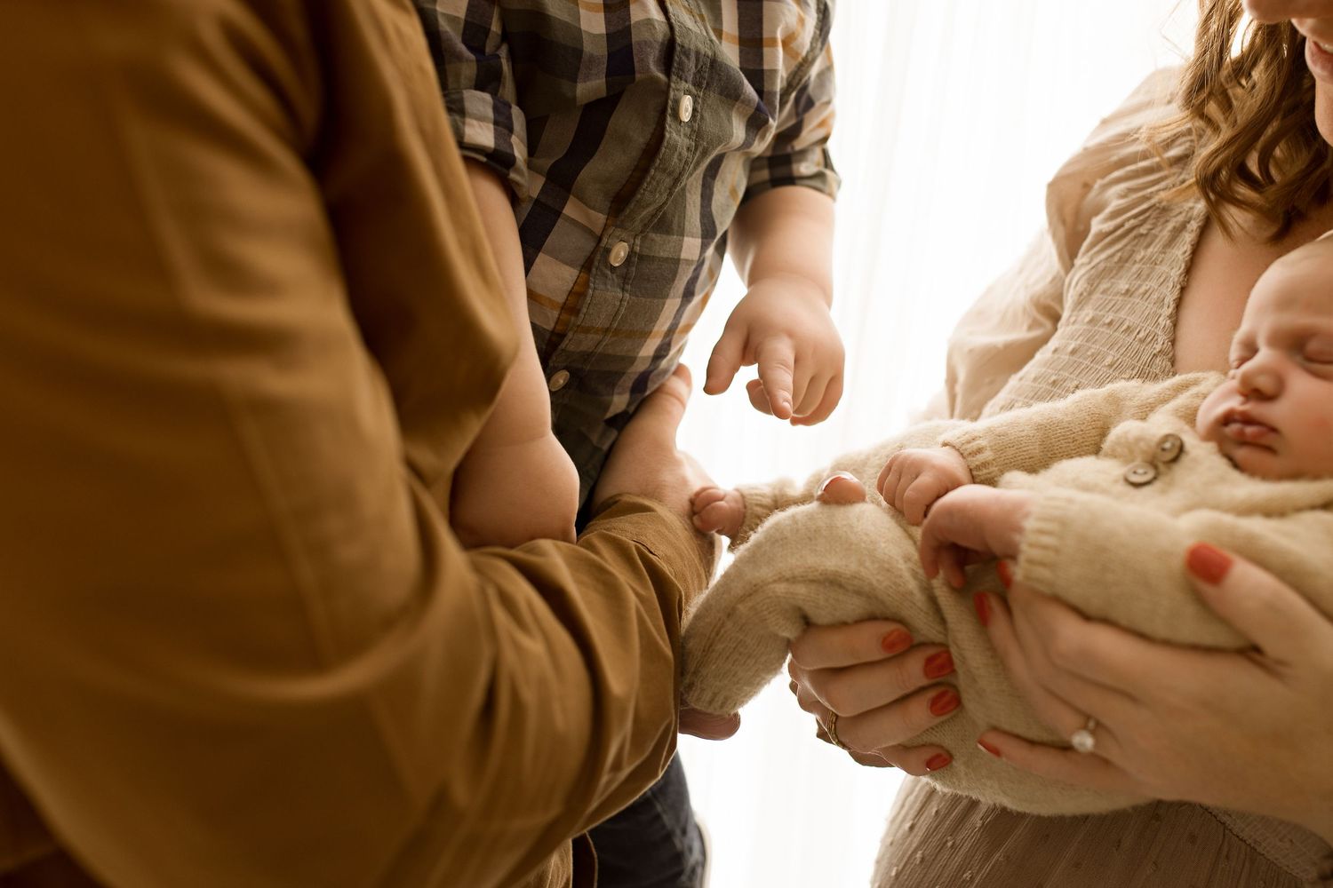 Close-up series of hands holding and comforting a small newborn baby wrapped in a blanket.