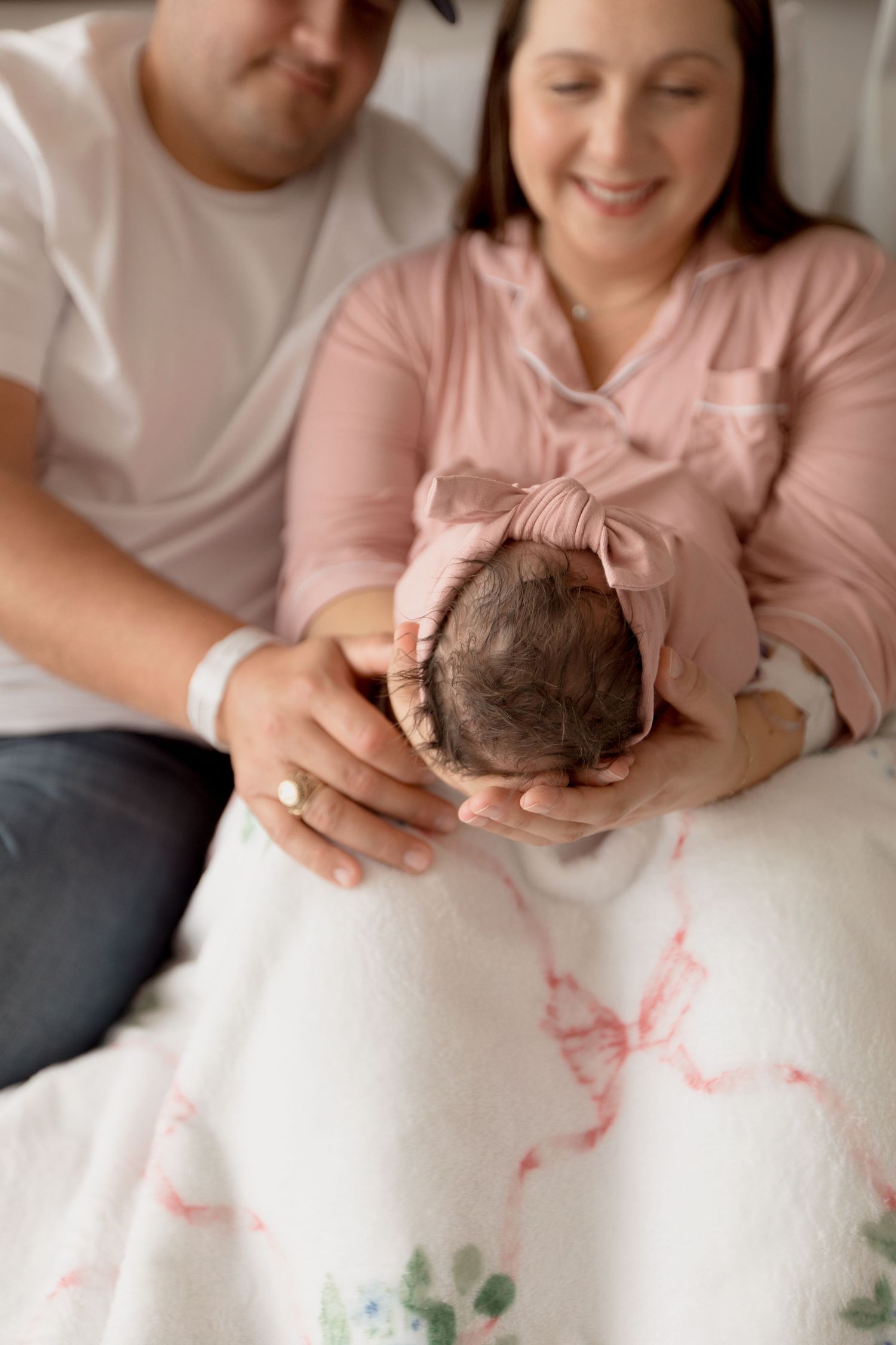 Hands hold and examine a round coconut against a white background with pink and green floral patterns.