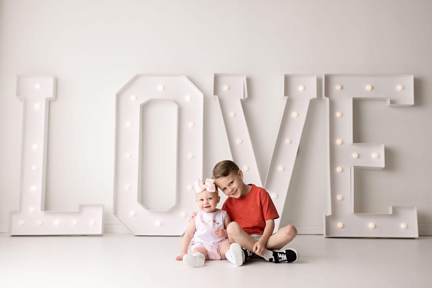 Clean minimalist portrait setup with large white LOVE letters against neutral background.