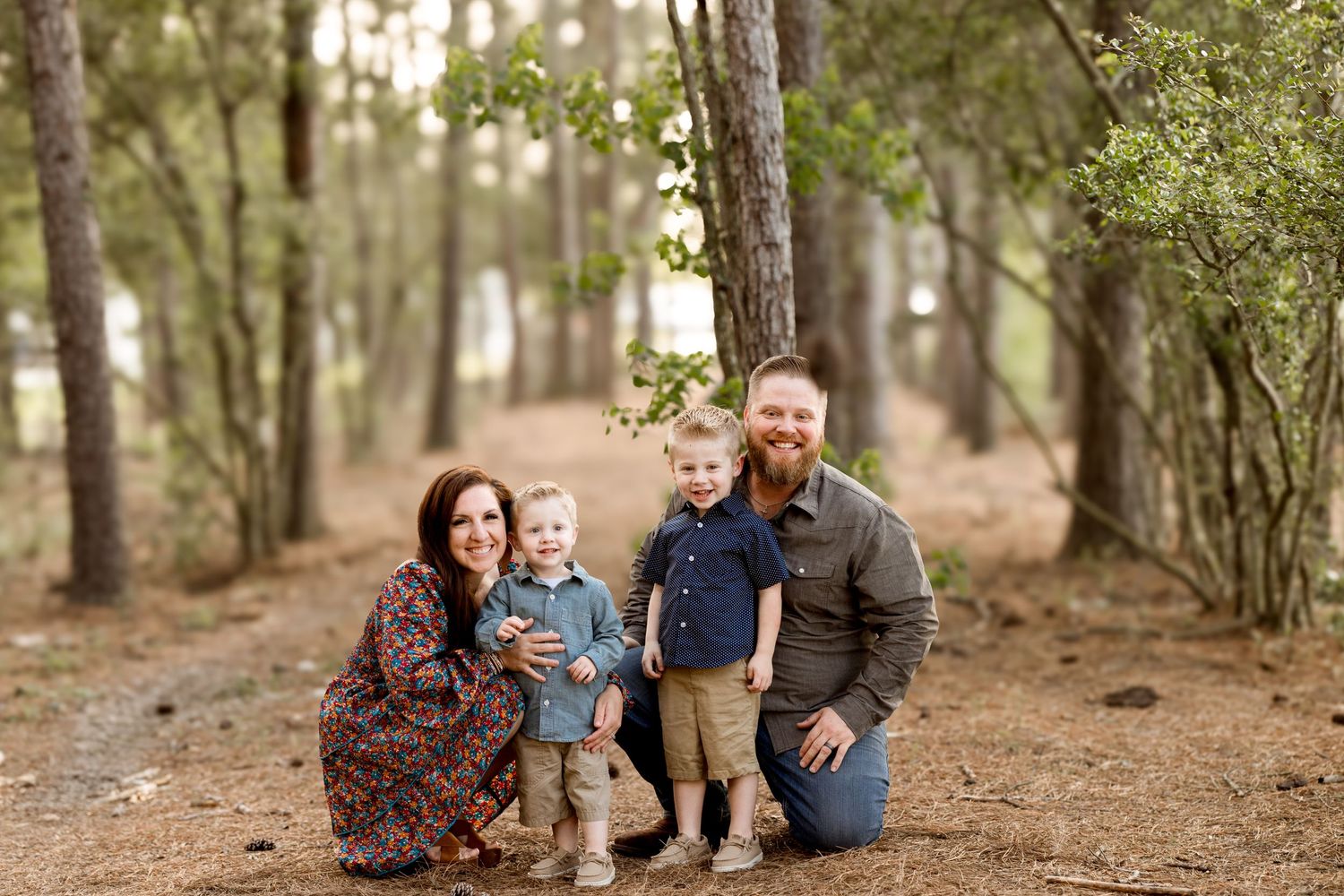 A family poses together on a wooded trail during an outdoor photo session.