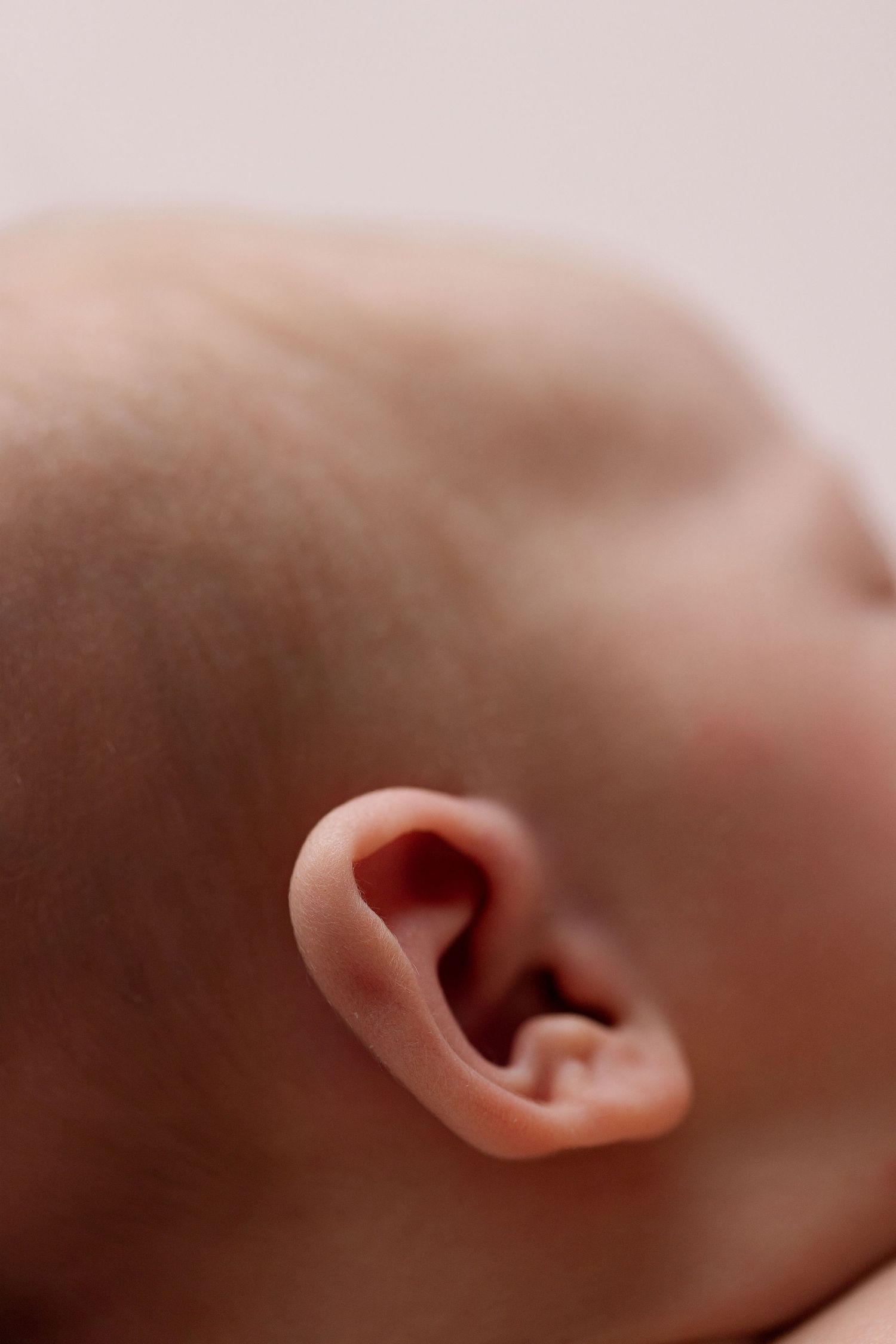 Close-up macro photo sequence showing a human ear from different angles against a soft pink background.