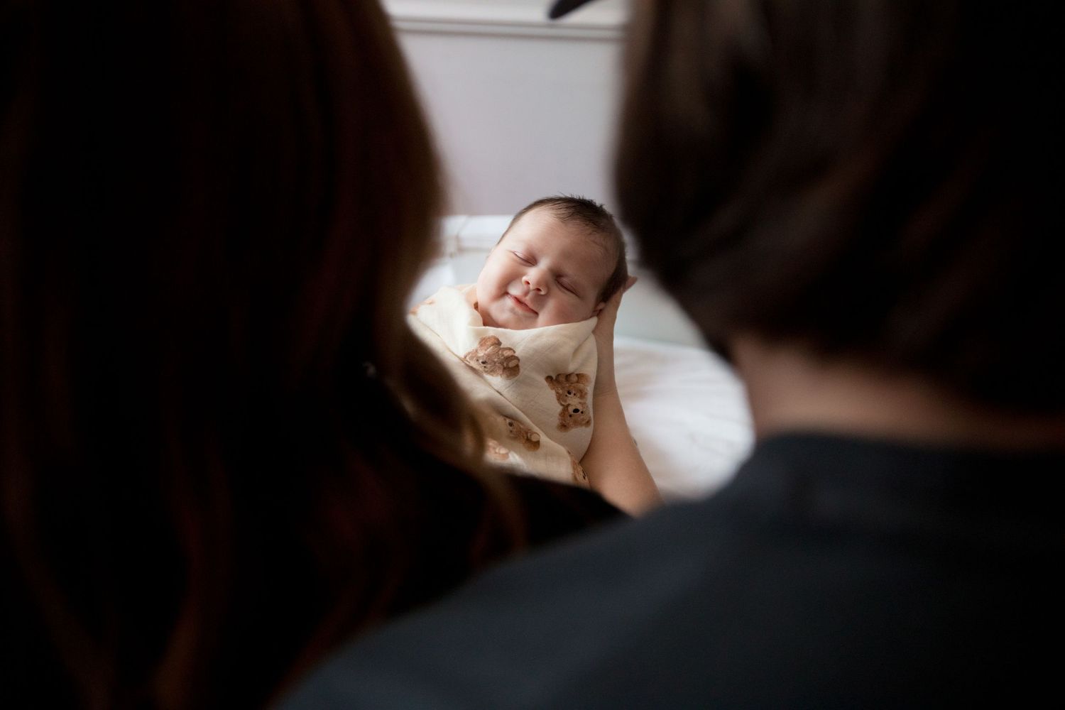 A sleeping newborn baby is viewed through caring hands in soft natural light during Fresh 48 session in Beaumont hospital.