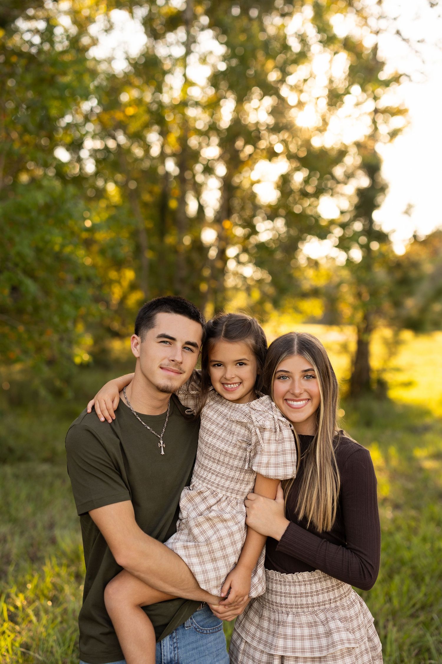 A family shares joyful moments together during a golden hour photoshoot in a natural outdoor setting.