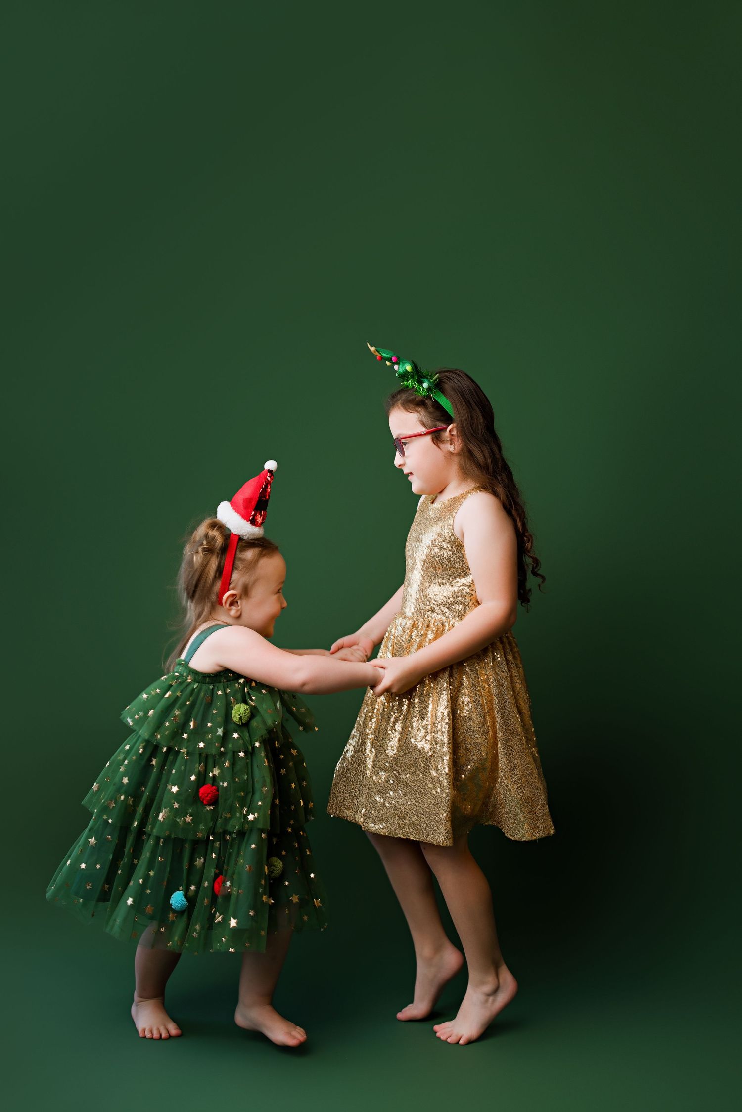 Two sparkly holiday dresses, one gold and one green with ornaments, captured against an emerald backdrop.