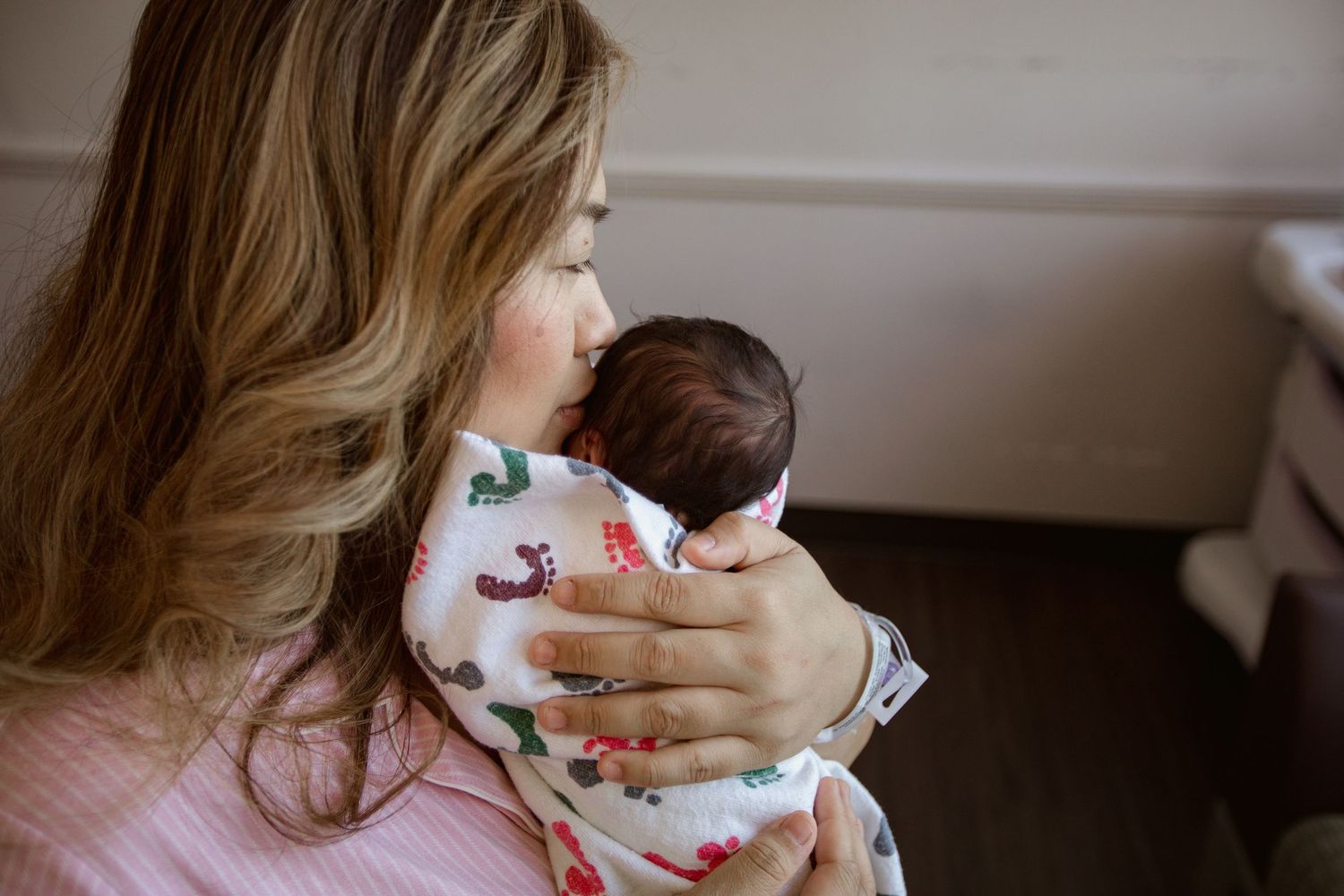 A sleeping newborn baby being cradled in a printed blanket.