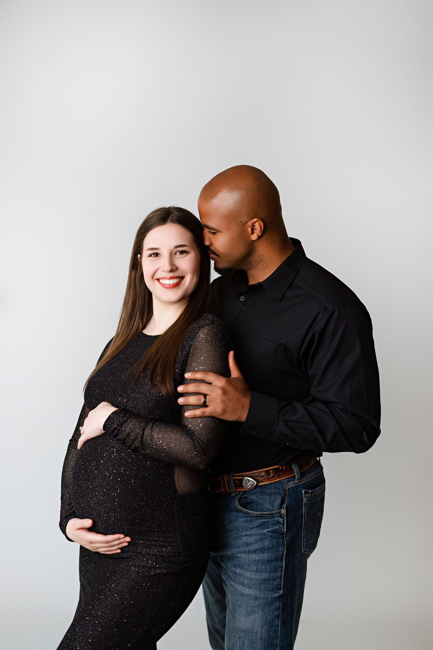 Intimate maternity photo of expectant couple embracing against light gray background with Bree Elle Photography in Port Neches, TX.