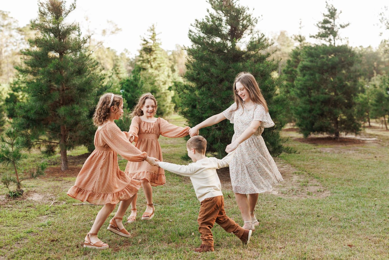 Playful family portraits with flowing dresses in rustic outdoor setting.
