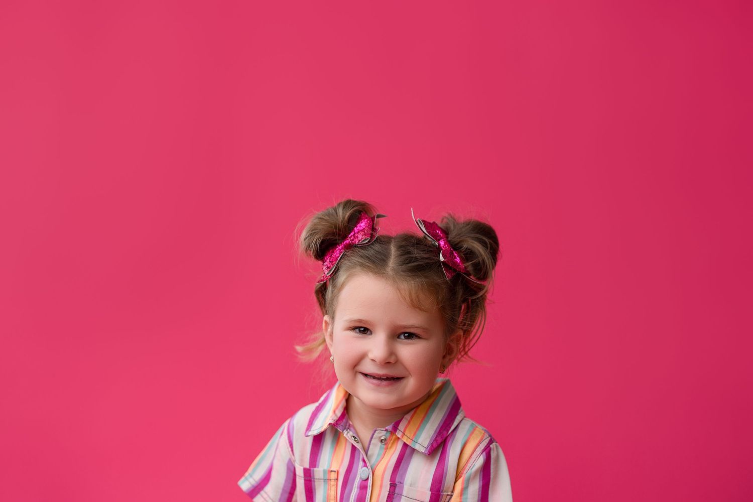 Adorable young child making different silly faces and expressions against a bright pink background.