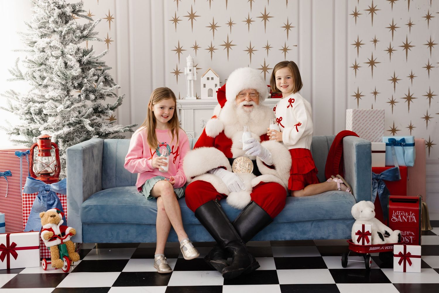 A festive Christmas photo shoot setup with a blue couch, white walls, and holiday decorations in a studio setting.