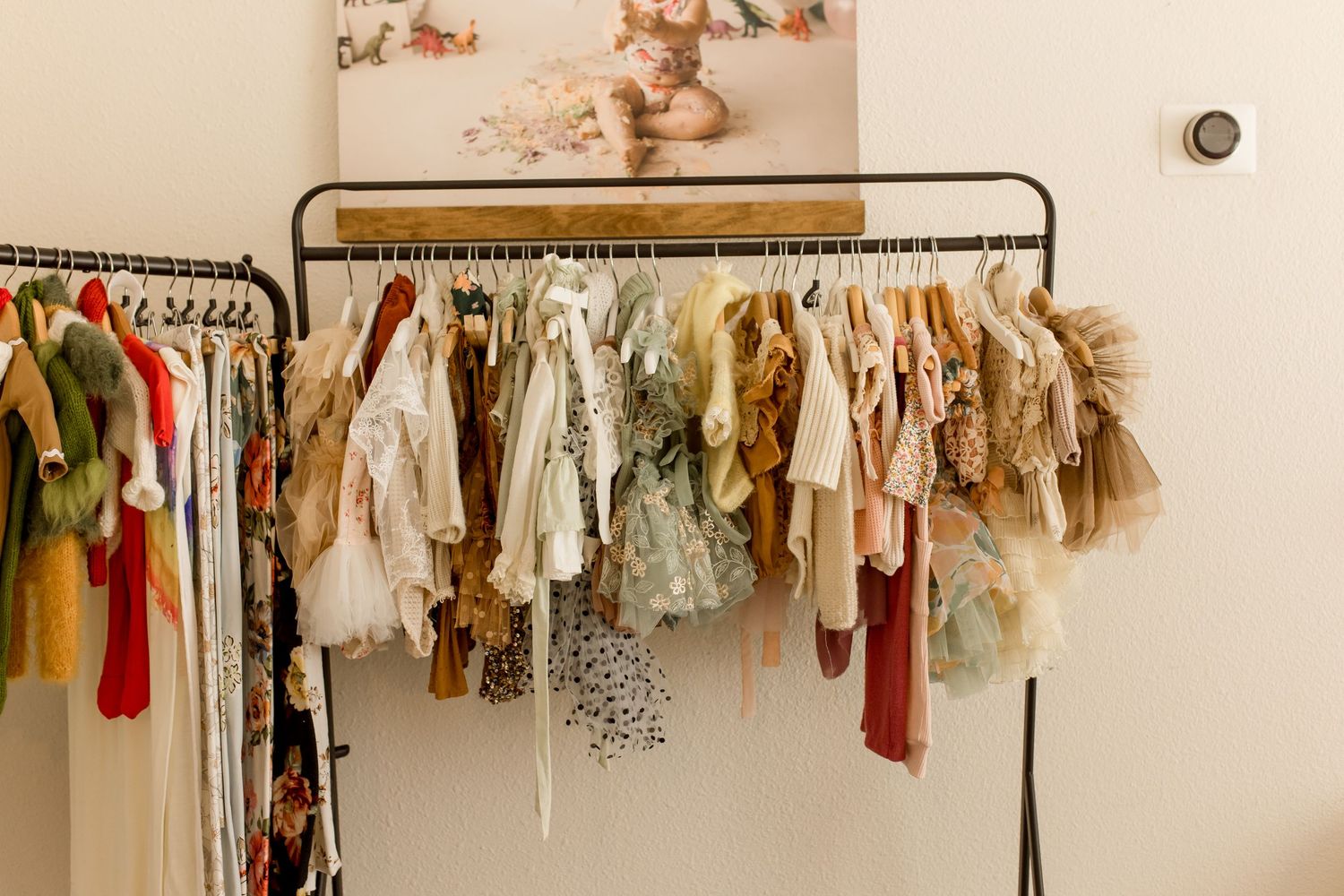 Rustic clothing rack with vintage-style baby clothes in earth tones.