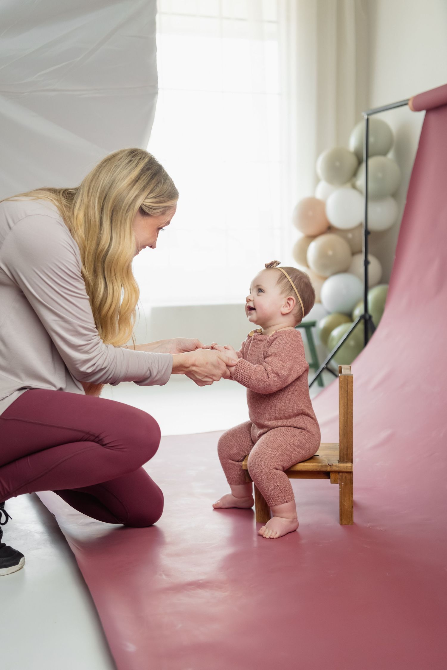 Behind the scenes photo shoot moment on pink backdrop with balloon decorations.