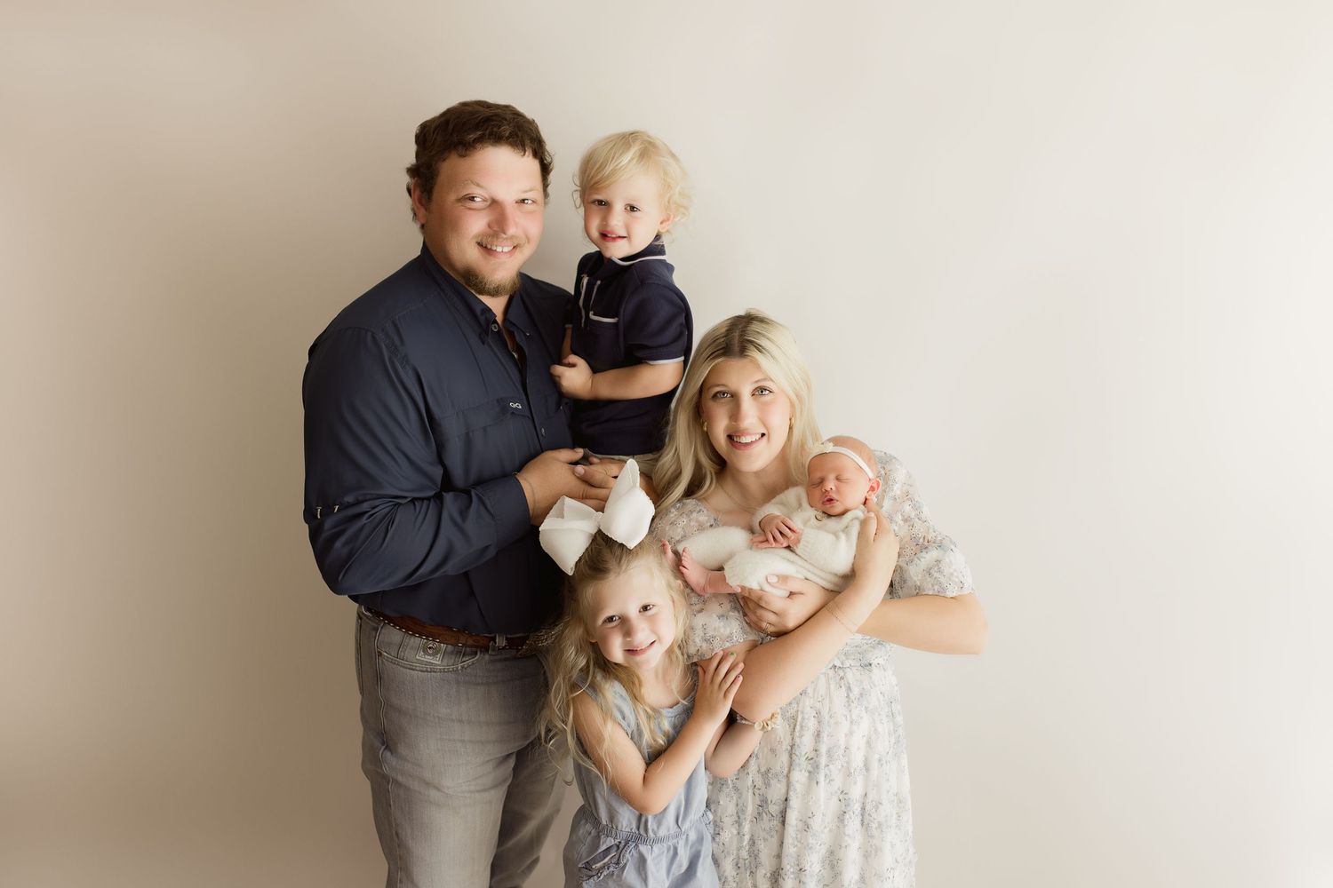 Family portrait session against a simple white backdrop showing loving interactions.