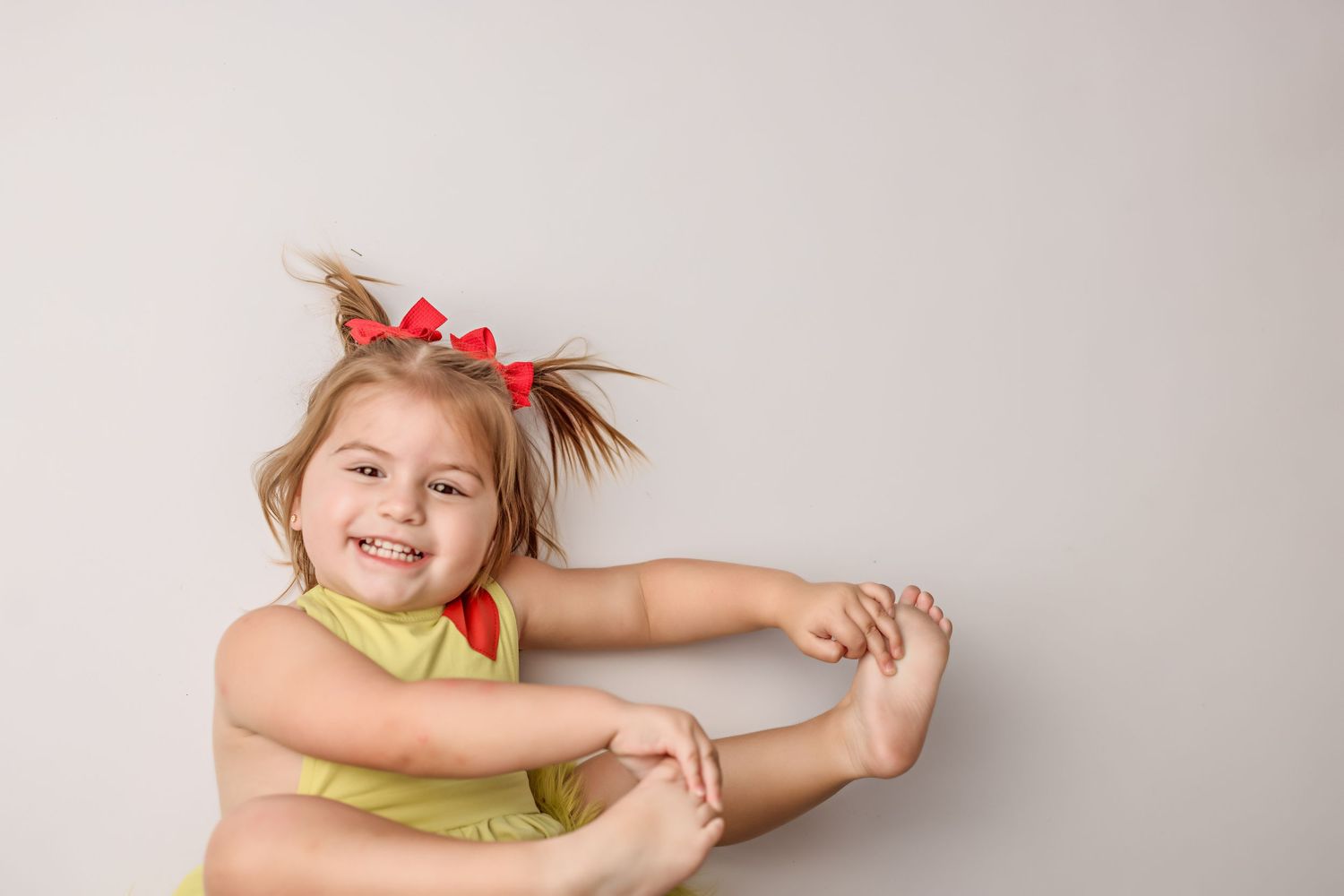 Studio portrait with yellow top and red hair accessories against neutral background.