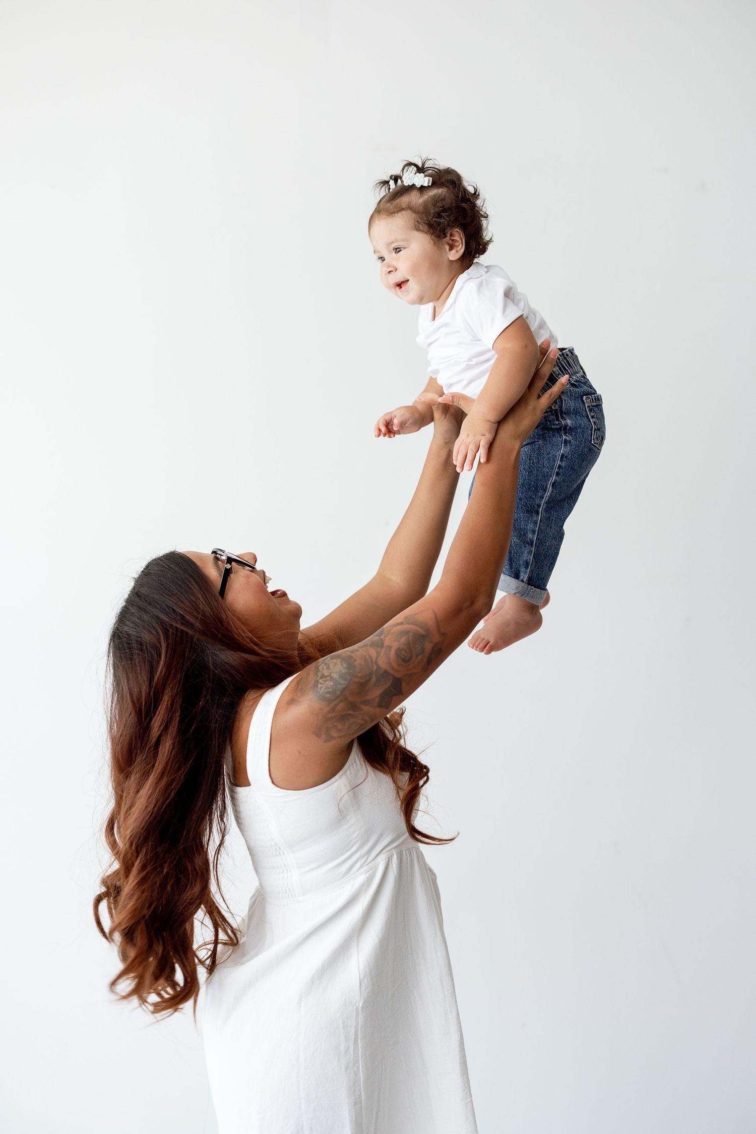 A parent in white holding up a small child wearing denim against a light background in three sequential poses.