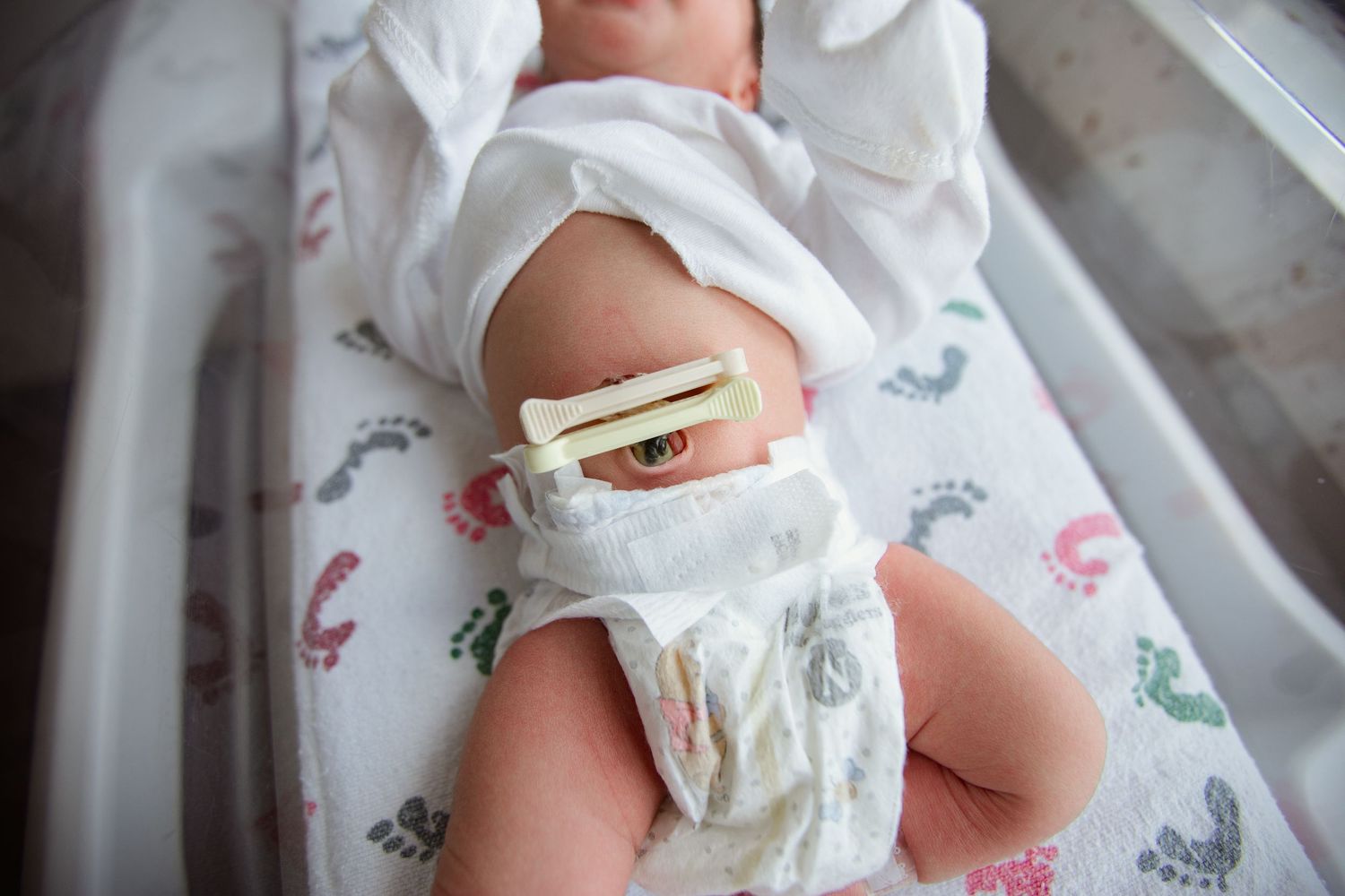 Close-up of baby wearing white diaper with colorful footprint pattern.