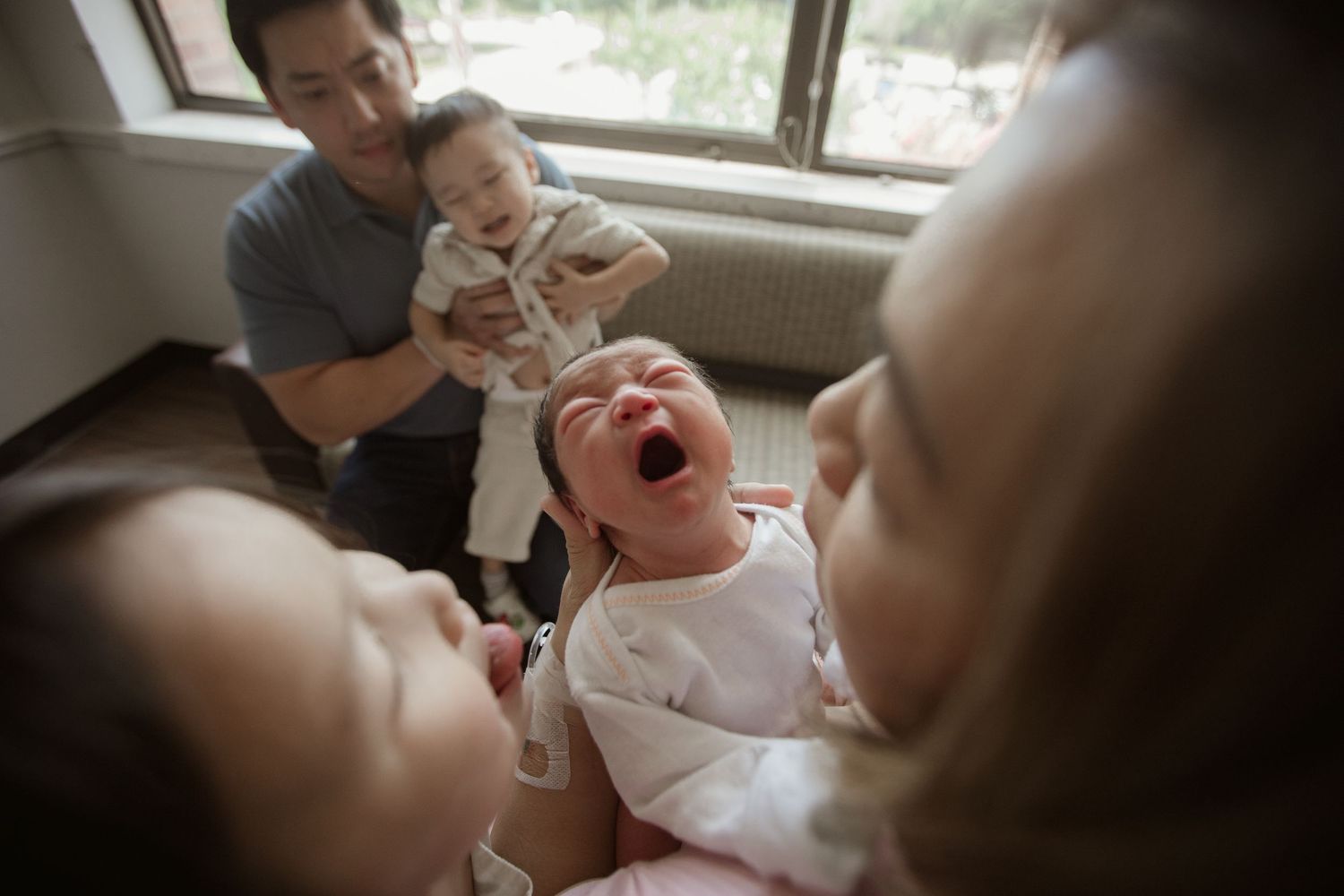 Family gathering with joyful laughter in a living room setting during Fresh 48 session in Beaumont hospital.