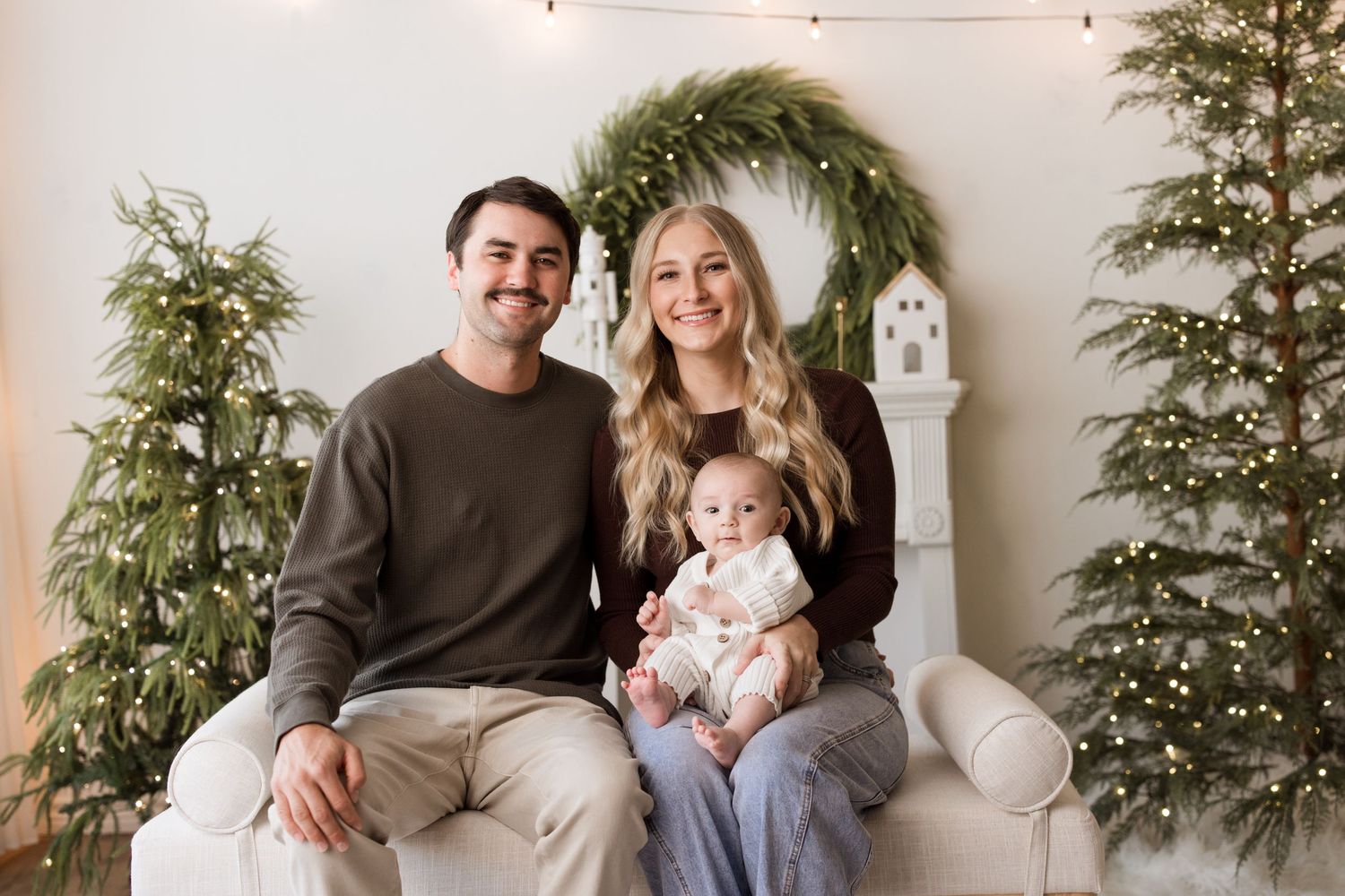 A series of six family portraits taken against a white wall with green plants showing loving moments between parents and child.