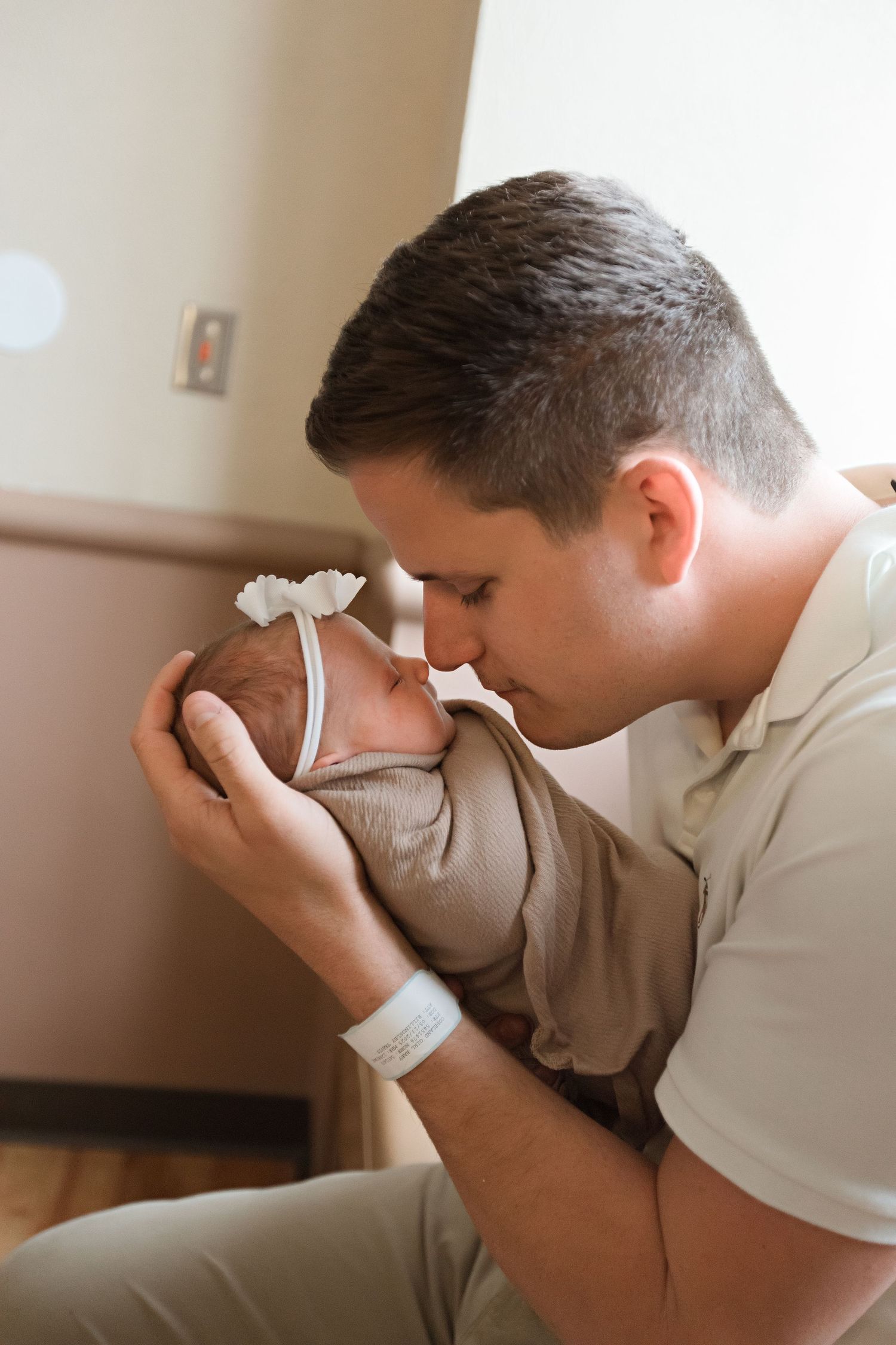 Tender moment of parent holding and kissing newborn baby in hospital room during Fresh 48 session in Beaumont hospital.