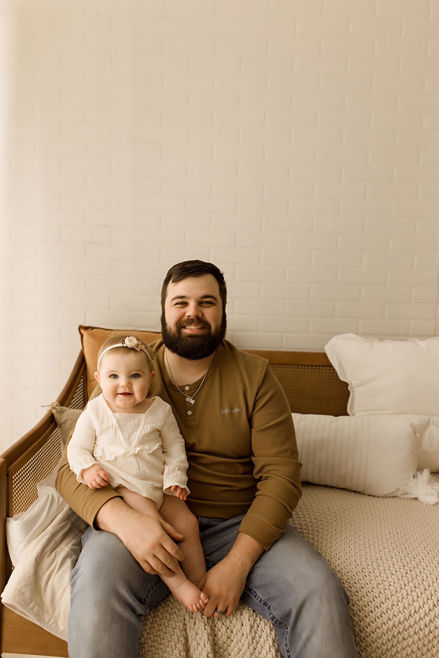 Family sitting on brown couch during cozy indoor photo session.