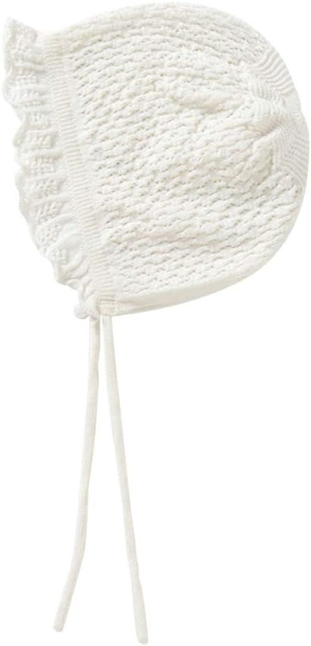 A repetitive pattern of white knit baby bonnets arranged in a row showing delicate crochet details.