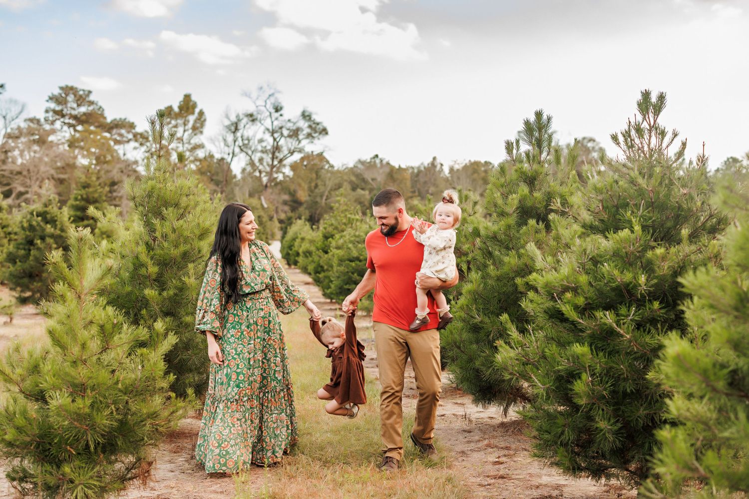 Family walking together among evergreen trees on sunny afternoon.