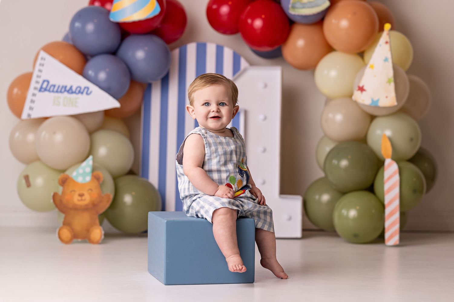 A birthday party setup with pastel balloons, teddy bears, and decorative elements against a neutral backdrop.