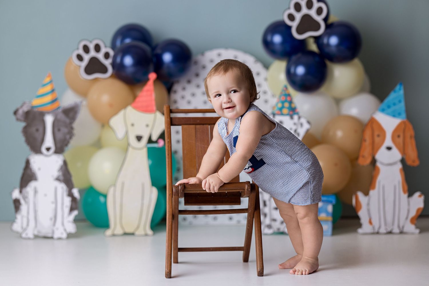 A series of baby milestone photos with a wooden chair and dog-themed backdrop showing growth progression over time.