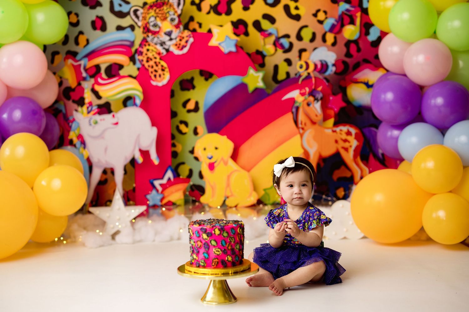 Colorful balloon garland decorates a festive birthday party space with cake and party decorations.