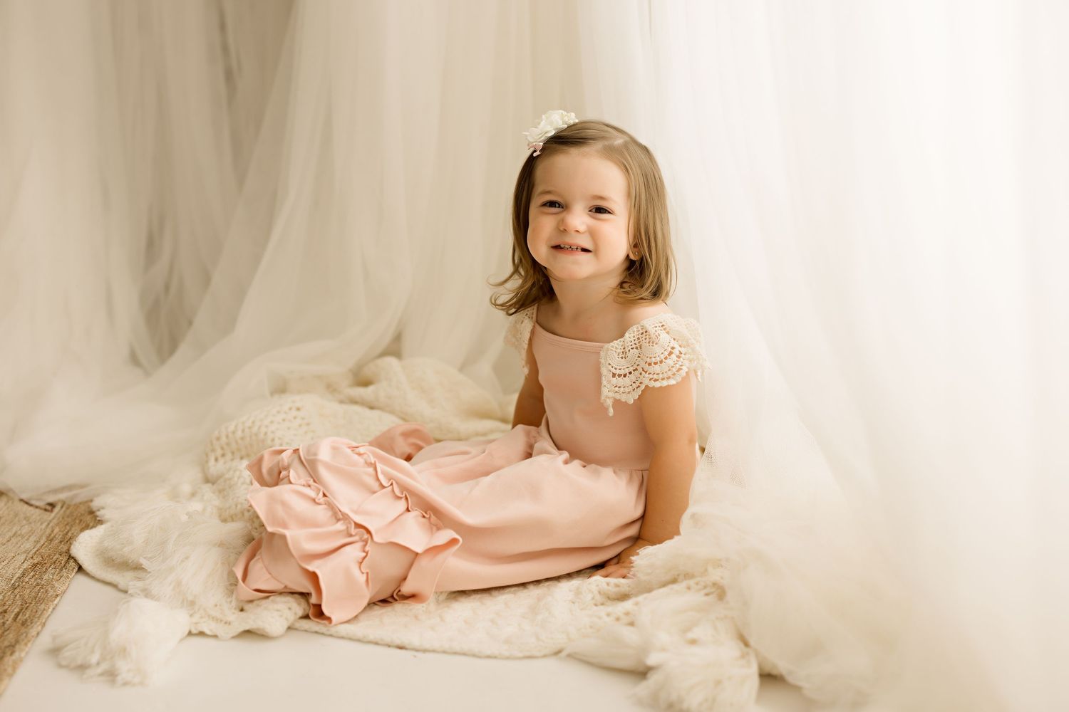 Dreamy portrait setup with white tulle backdrop and soft pink dress.