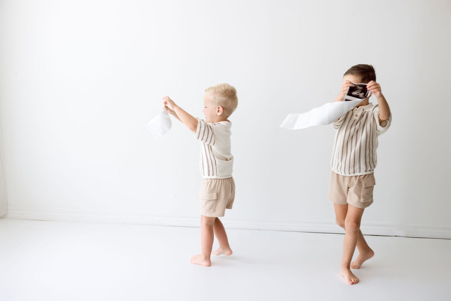 Progression of a baby learning to walk from sitting to standing shown in a minimalist white studio setting.