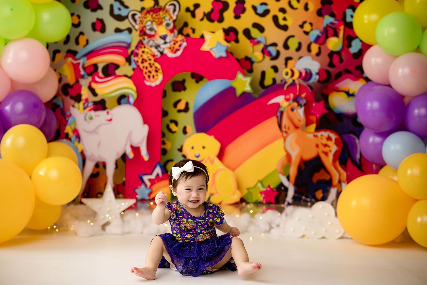 Colorful birthday party setup with rainbow backdrop, animal decorations, leopard print patterns and balloons.