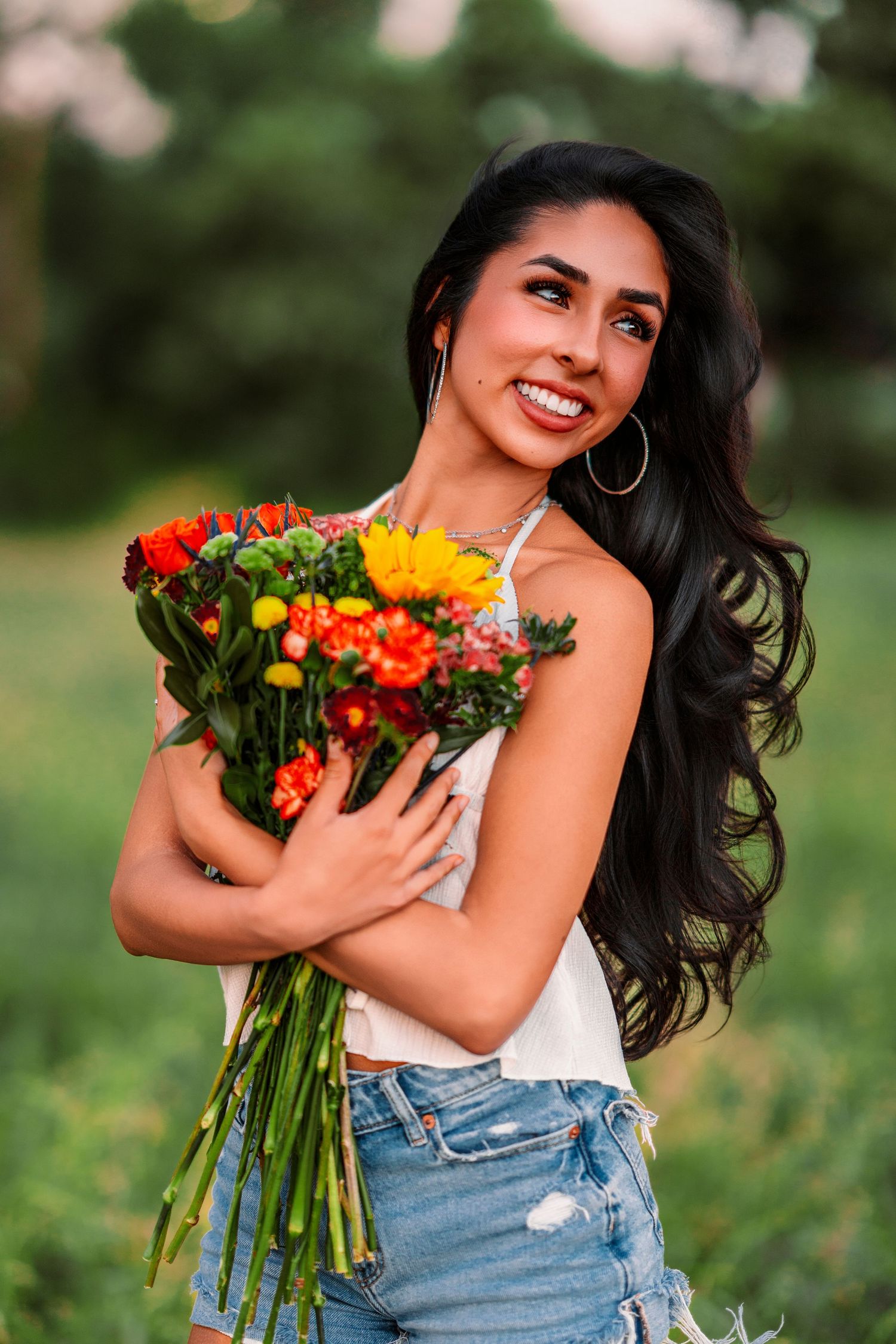 A summer portrait with a vibrant bouquet of orange and yellow flowers in a field.