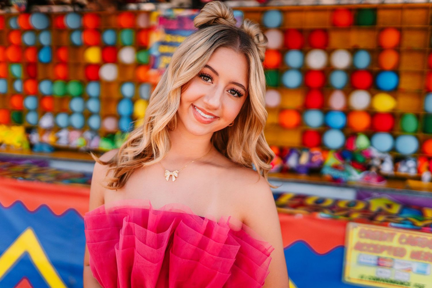 Carnival lights and colorful decorations create a festive backdrop for a pink fashion shoot.