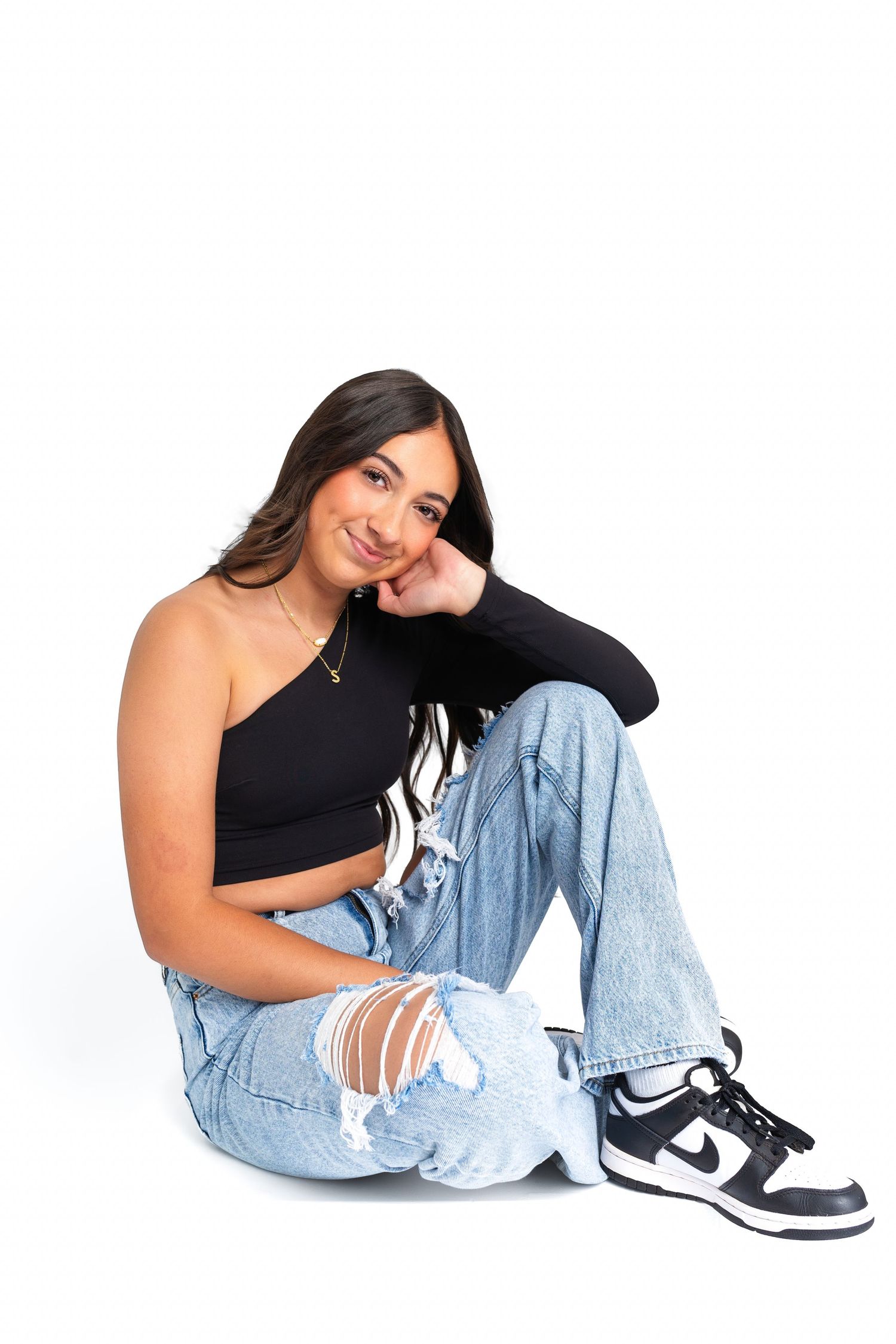 Casual lifestyle portraits against white background wearing ripped jeans and black top.
